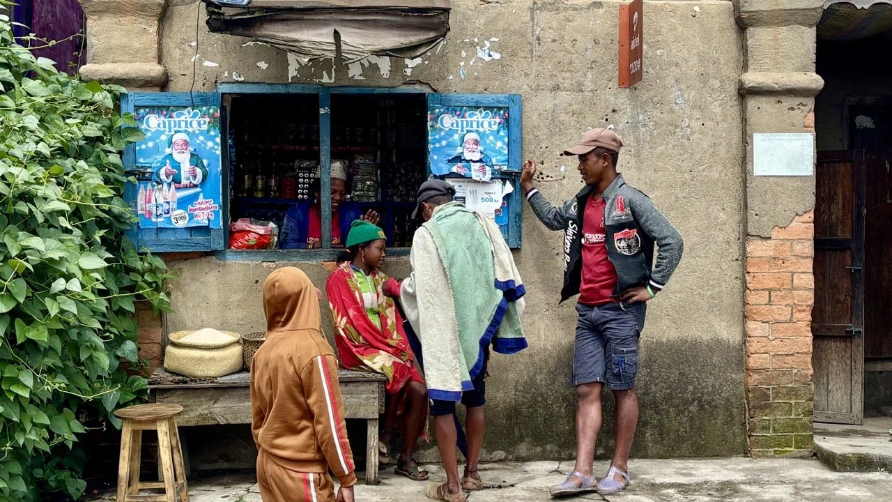 市集攤販環境人像：賣菜的婦女微笑與交易瞬間，捕捉在地人情與市場節奏；Ranomafana market vendor portrait — a smiling woman selling vegetables, capturing local warmth and market rhythm.