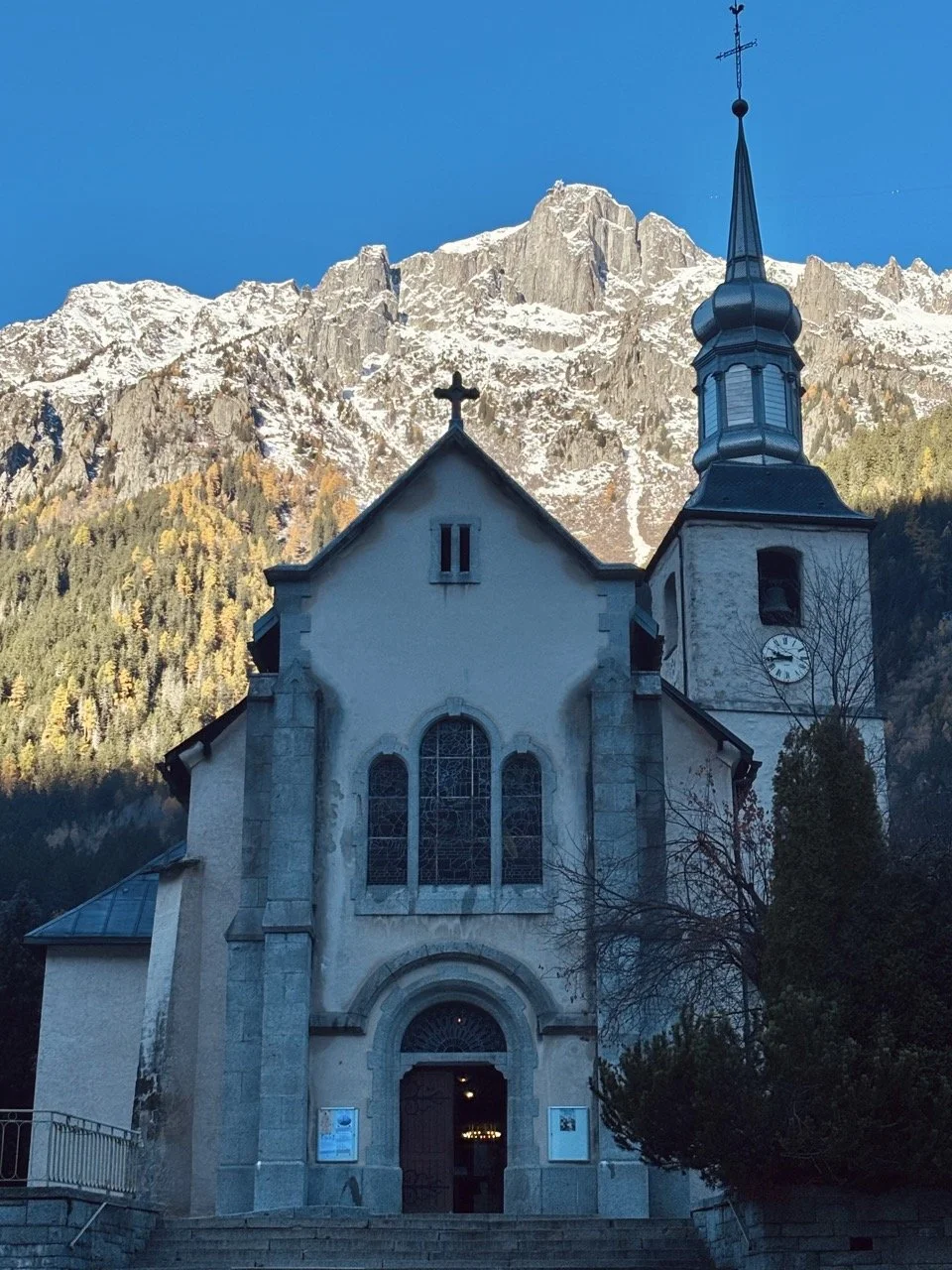 Chamonix 市區教堂廣場與阿爾卑斯山背景的人文街景，黃昏燈光與山景融合；Chamonix town center church square with Alpine backdrop, golden hour street scene.