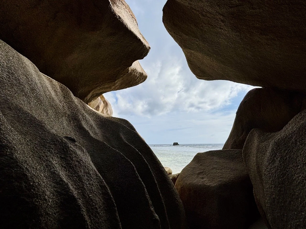旅客漫步於拉迪格島 Anse Source d’Argent 沙灘，近距離欣賞花崗岩與清澈海水的自然景色。
