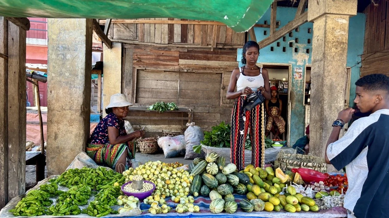 Ranomafana 在地市集水果攤：色彩繽紛的芒果、菠蘿與香蕉堆疊，展現馬達加斯加熱帶農產與市集生活；Ranomafana local market fruit stand — colorful mangoes, pineapples and bananas showcasing Madagascar’s tropical produce and market life.
