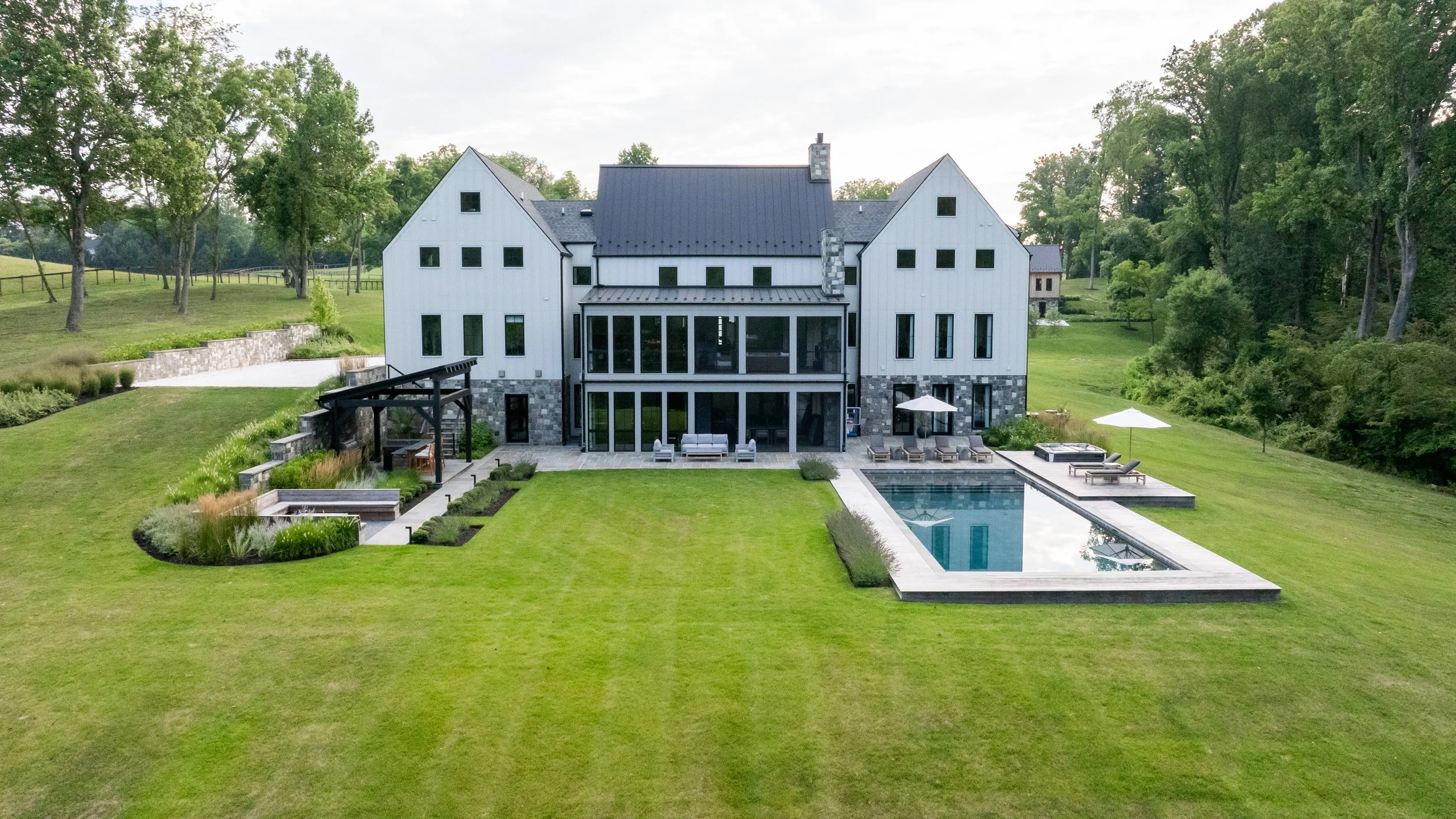 Modern Tudor home in Maryland with outdoor kitchen, pool, and spa, designed by residential  Landscape Architects, FORM Garden Design.