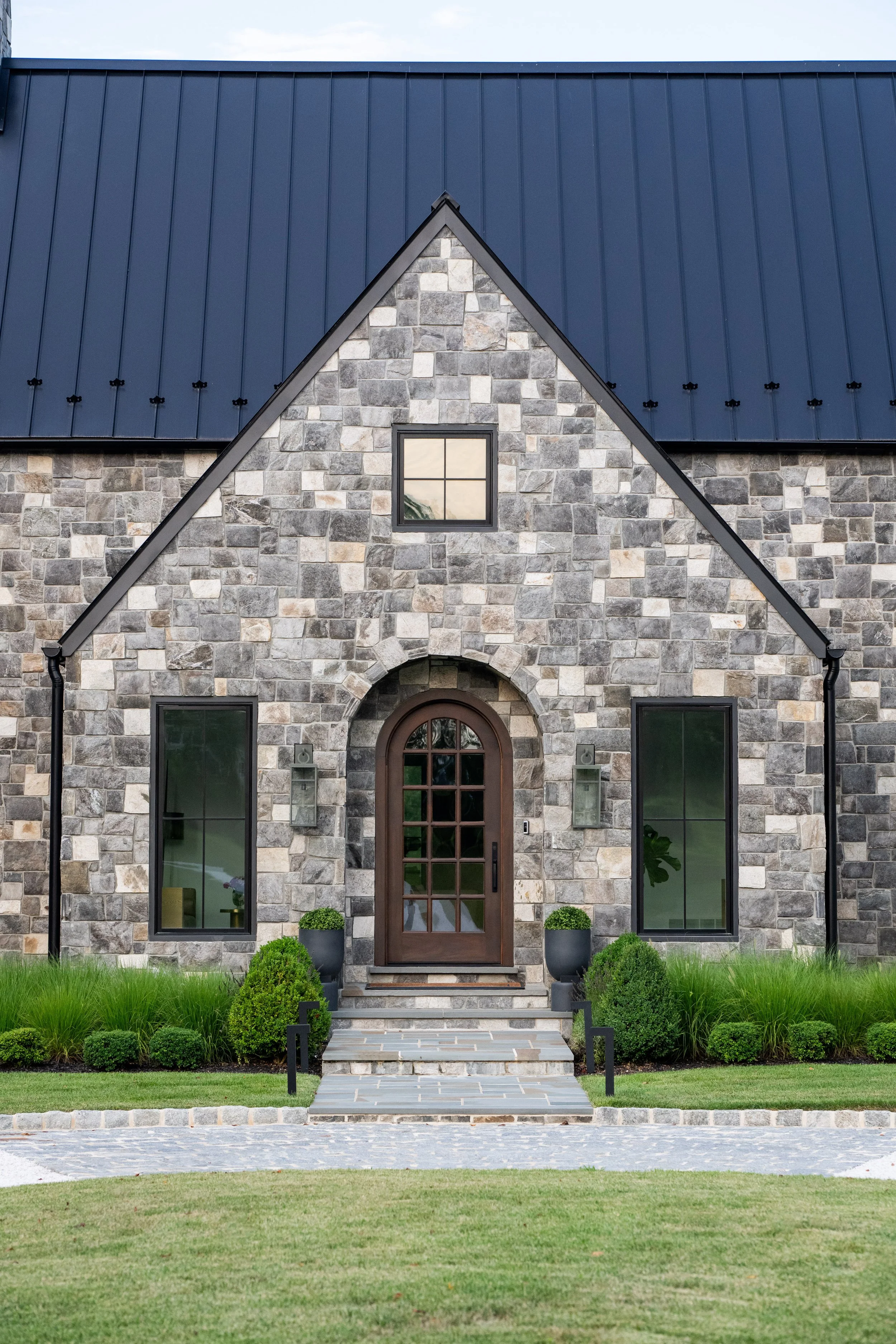 Stone Tudor home entrance, with simple modern planting by FORM Garden Design.