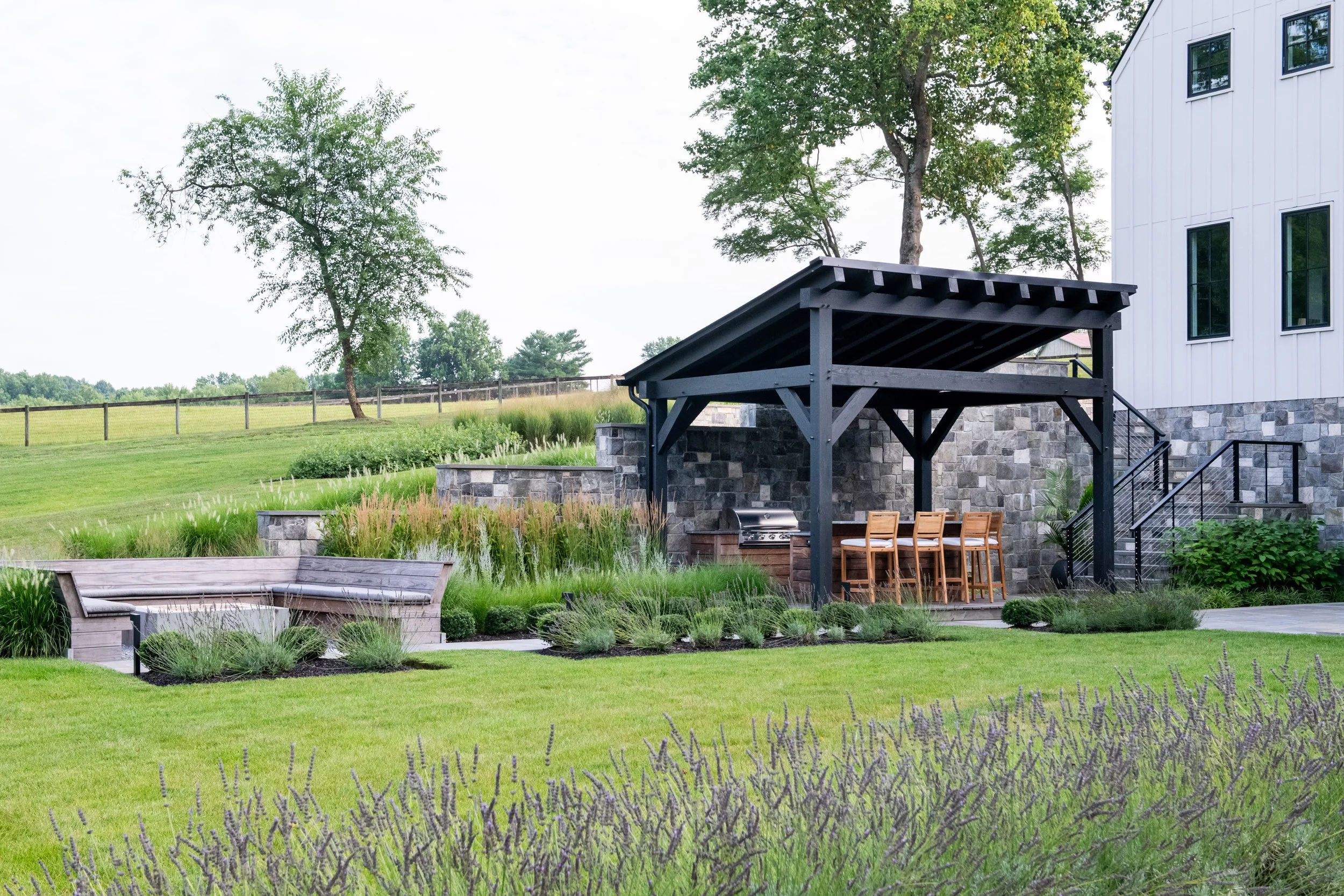 Outdoor entertainment space with outdoor kitchen, dining table, and covered bar in Bel Air, Maryland.  Designed by FORM Garden Design.