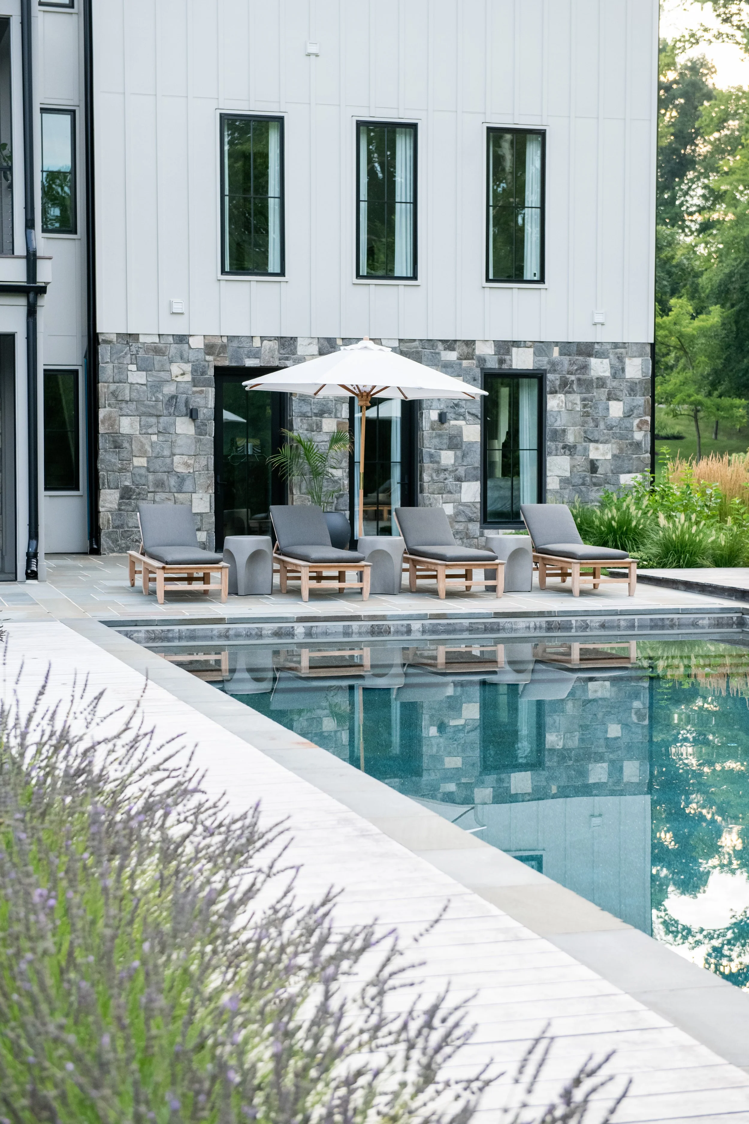 Lounge chairs by the pool with bluestone paving and naturalistic planting designed by Kevin Gaughan with FORM Garden Design.