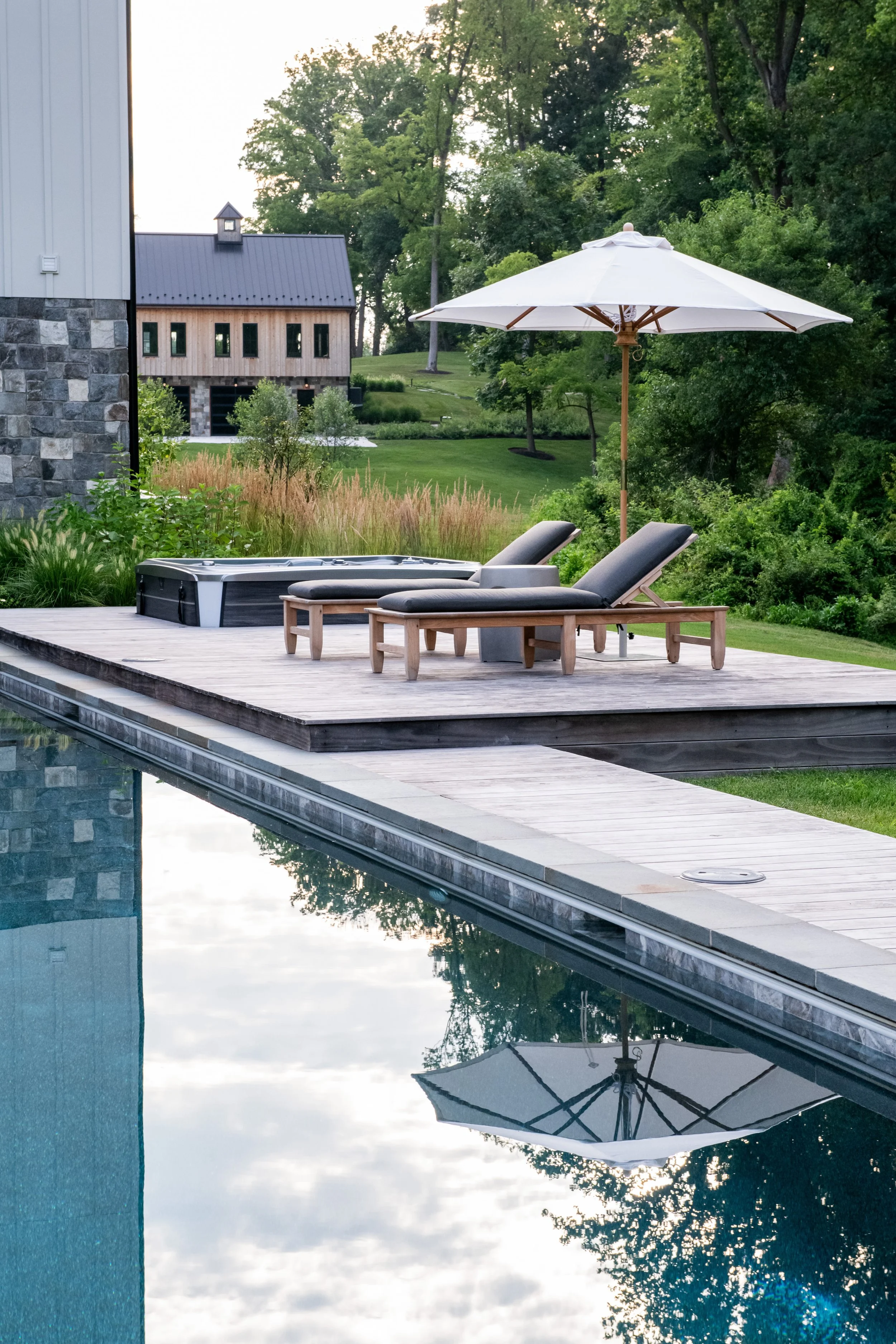 Bluestone edged pool with in-ground hot tub spa and lounge chairs in Bel Air Maryland, designed by FORM Garden Design.
