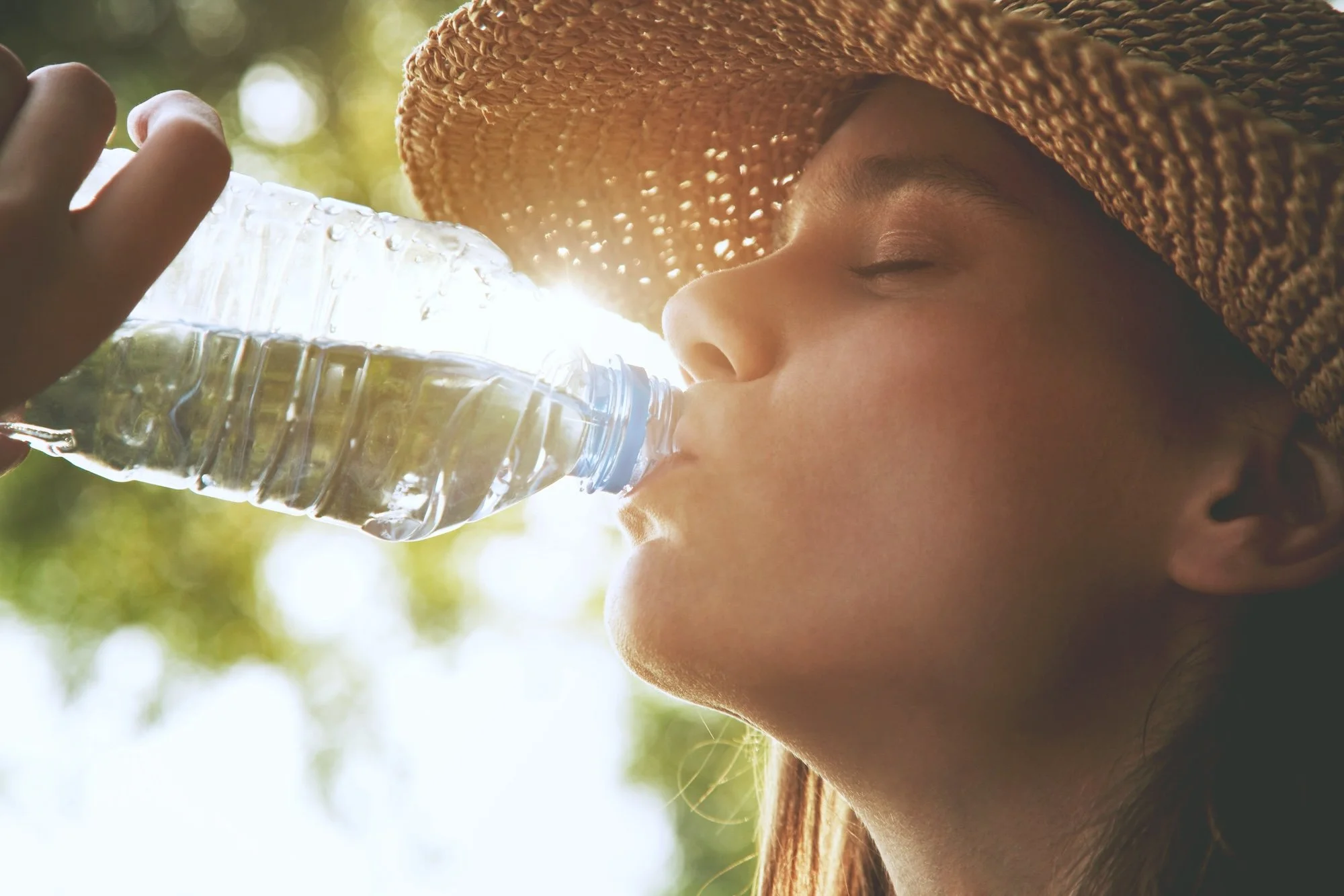 young woman drinking water while enjoying the outdoors stays hydrated but also protects her teeth