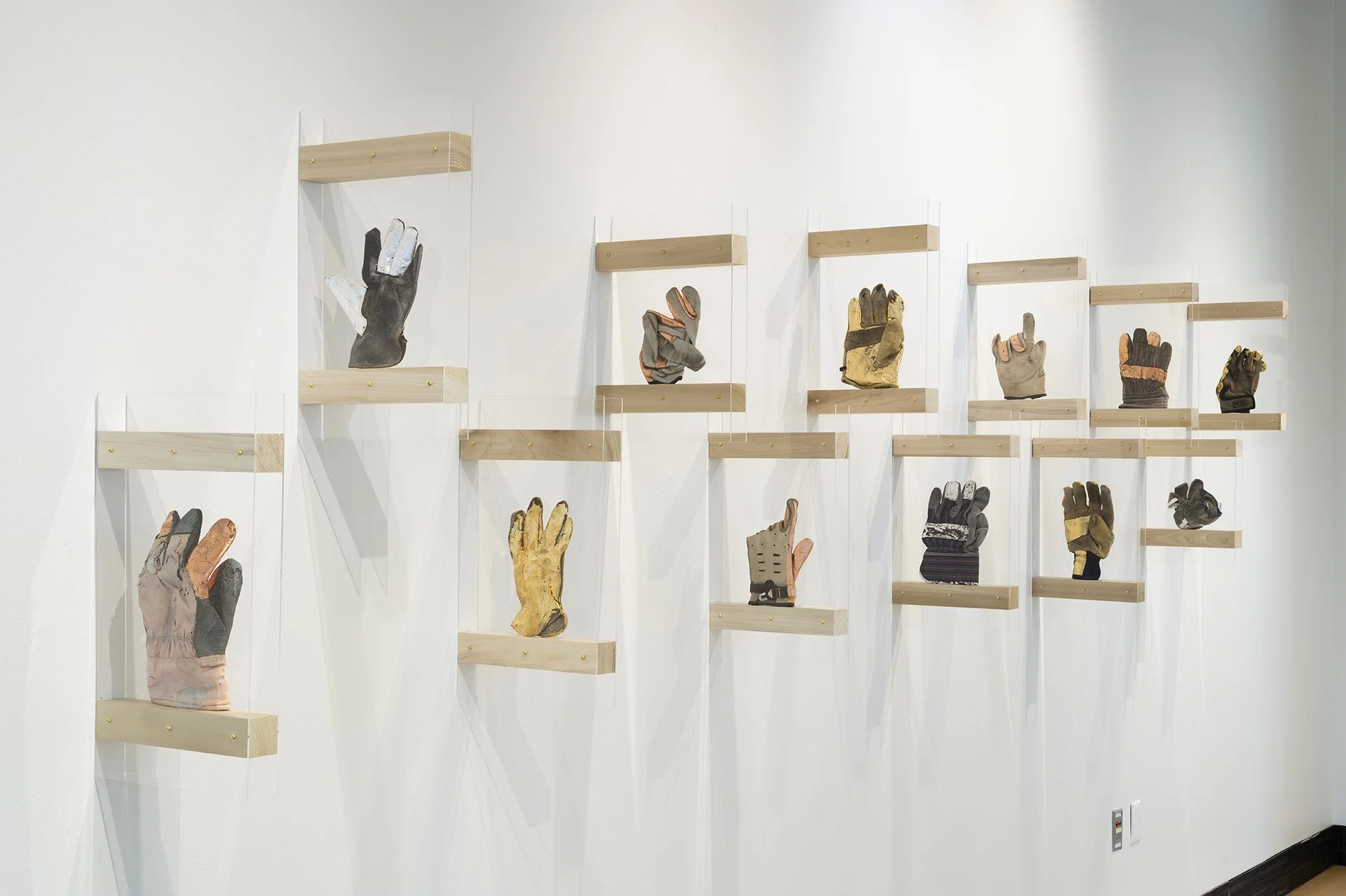 Labor Objects: gloves (installation view), Found work gloves gilded in gold, silver, and copper leaf, 39” h x 32’w, 2025