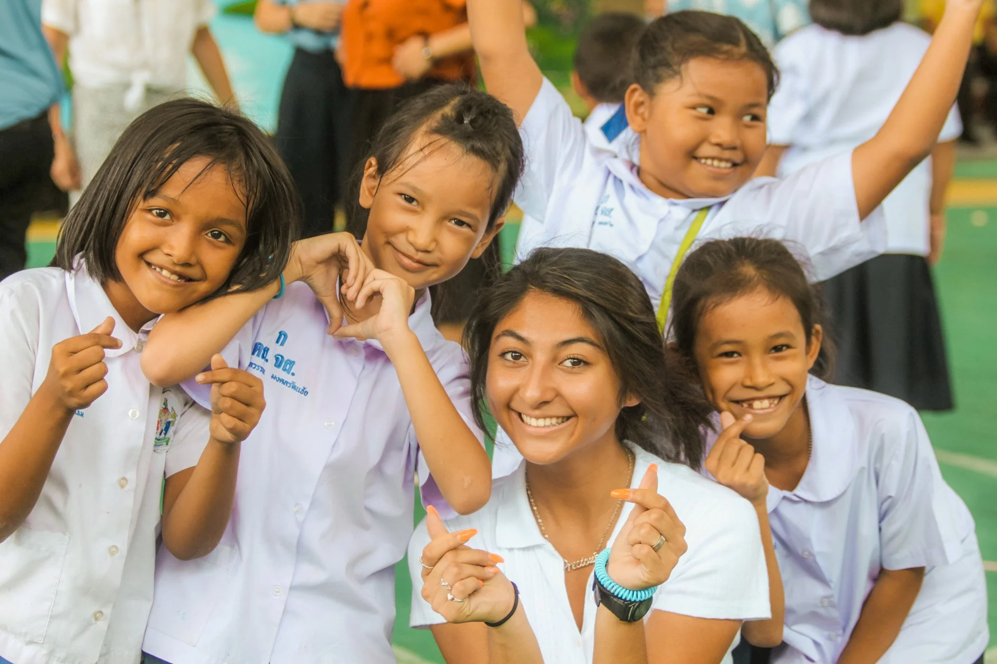 An RLT leader making a heart shape with local schoolchildren