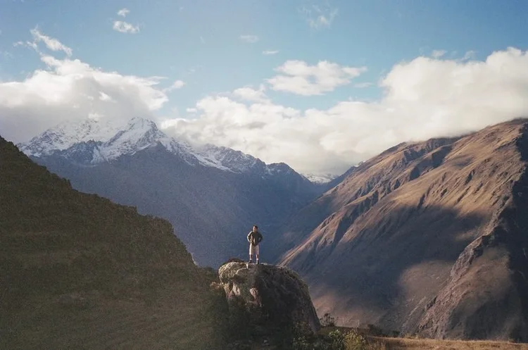 A traveler standing on a cliff overlooking mountains