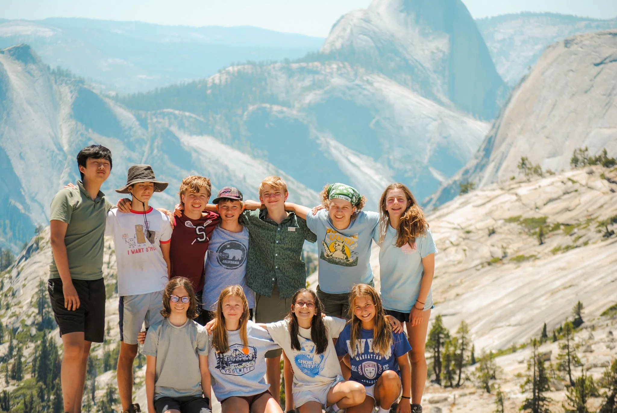 A trip group with arms around each other at a mountain summit