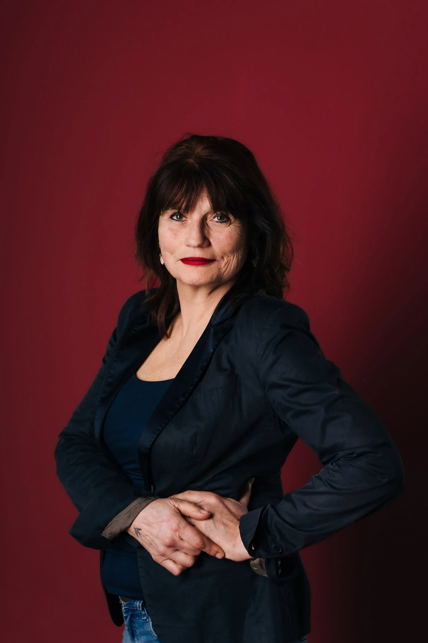 Portret van Sheila Struyck in pak voor een rode achtergrond