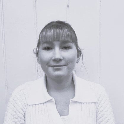 Black and white photo of a woman with light-colored hair and a fringe, smiling slightly, wearing a light-colored sweater.