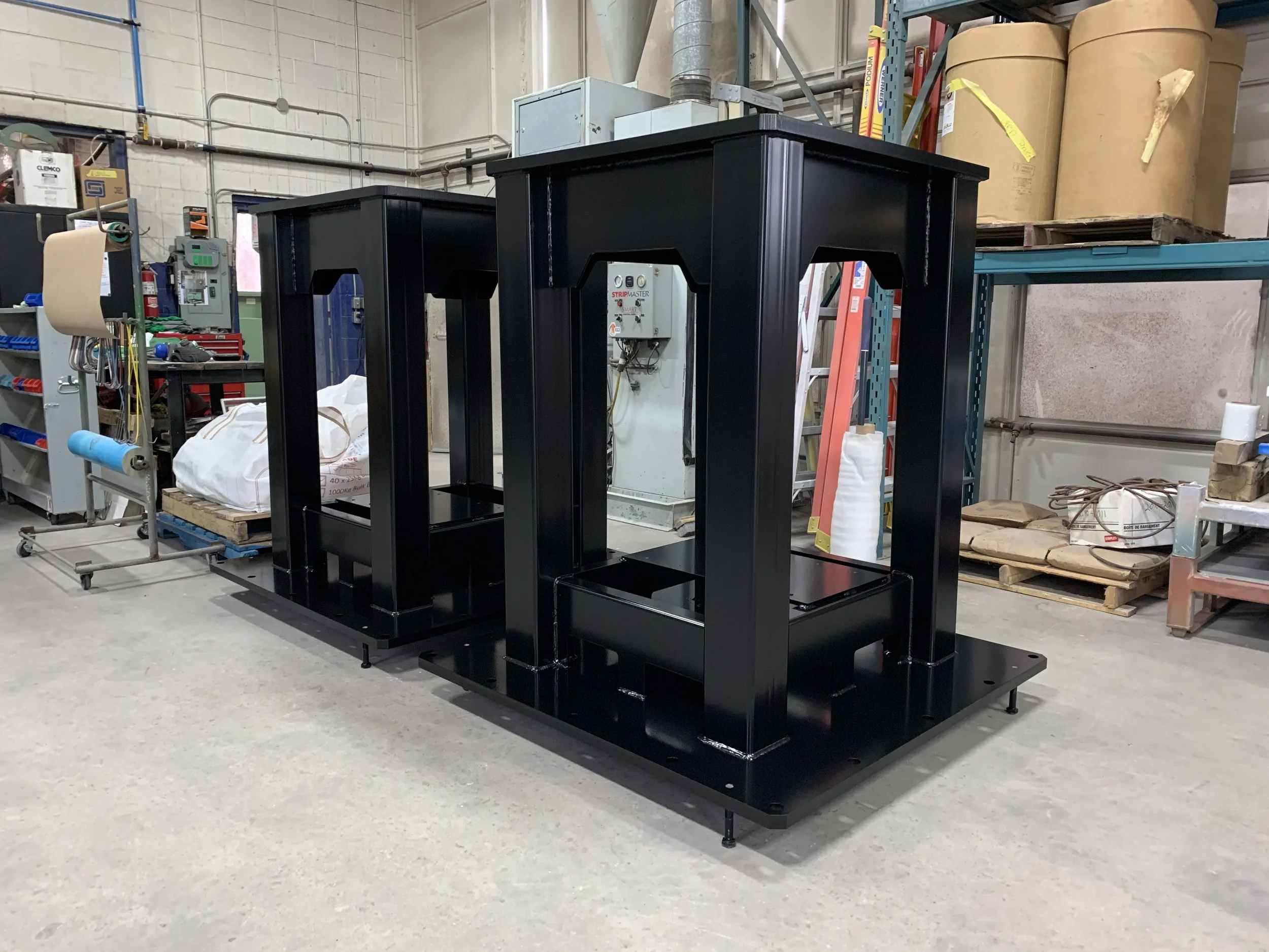 A black industrial powder coated metal shelving or frame structure in a workshop or warehouse setting.