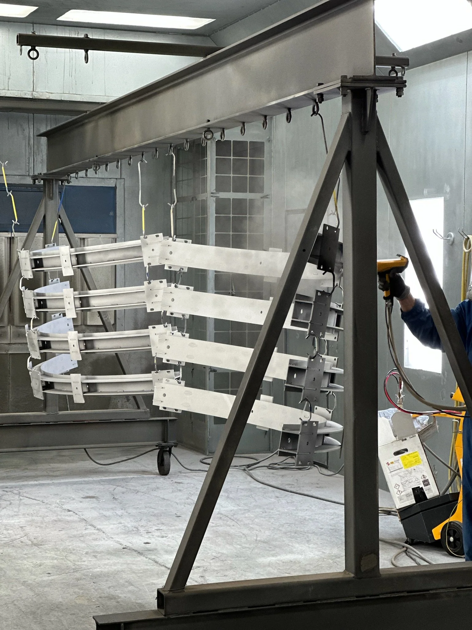 large awkward parts being powder coated in a paint booth