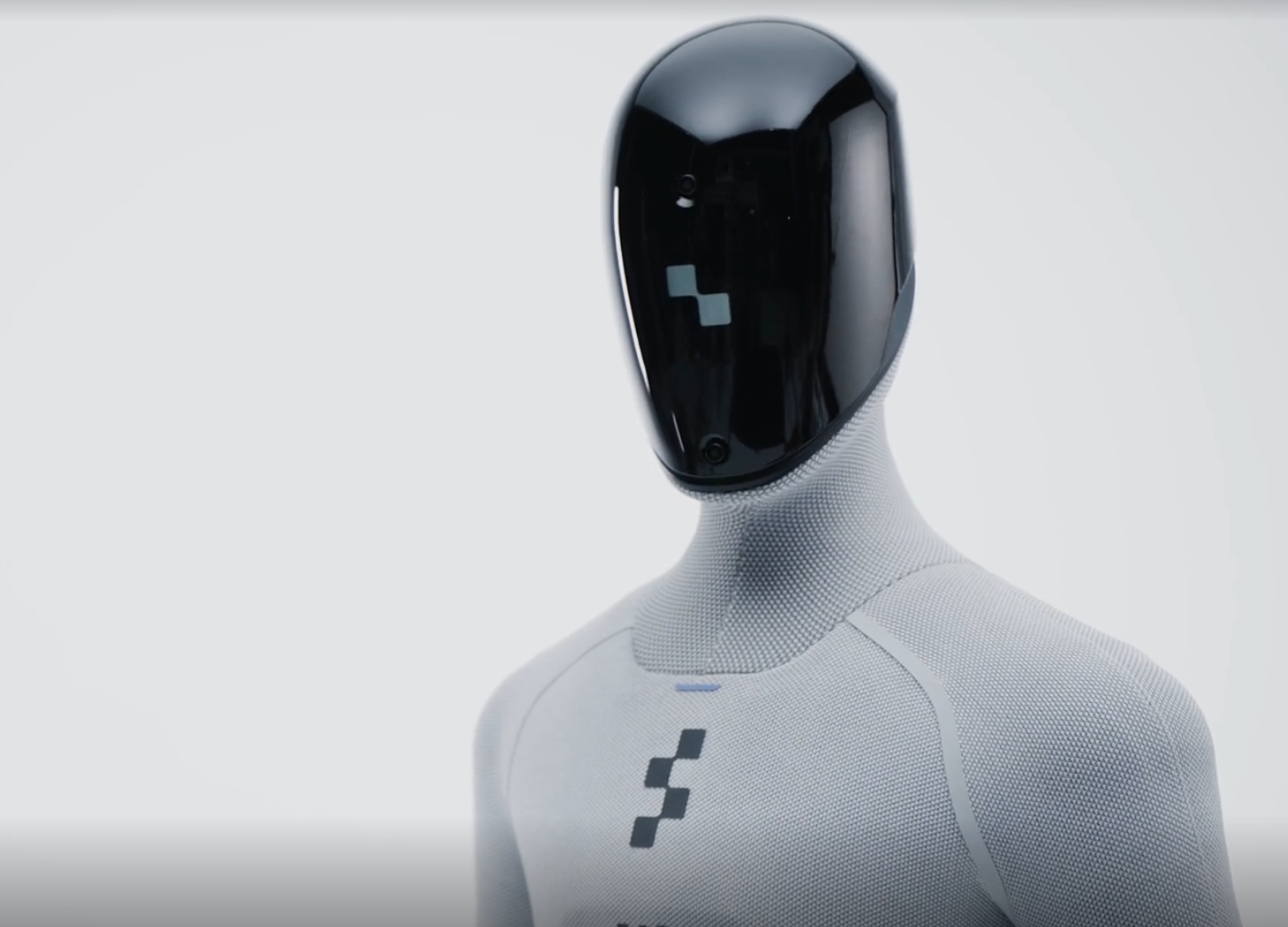 A humanoid robot with a sleek black faceplate and a white textured body, standing against a plain background.