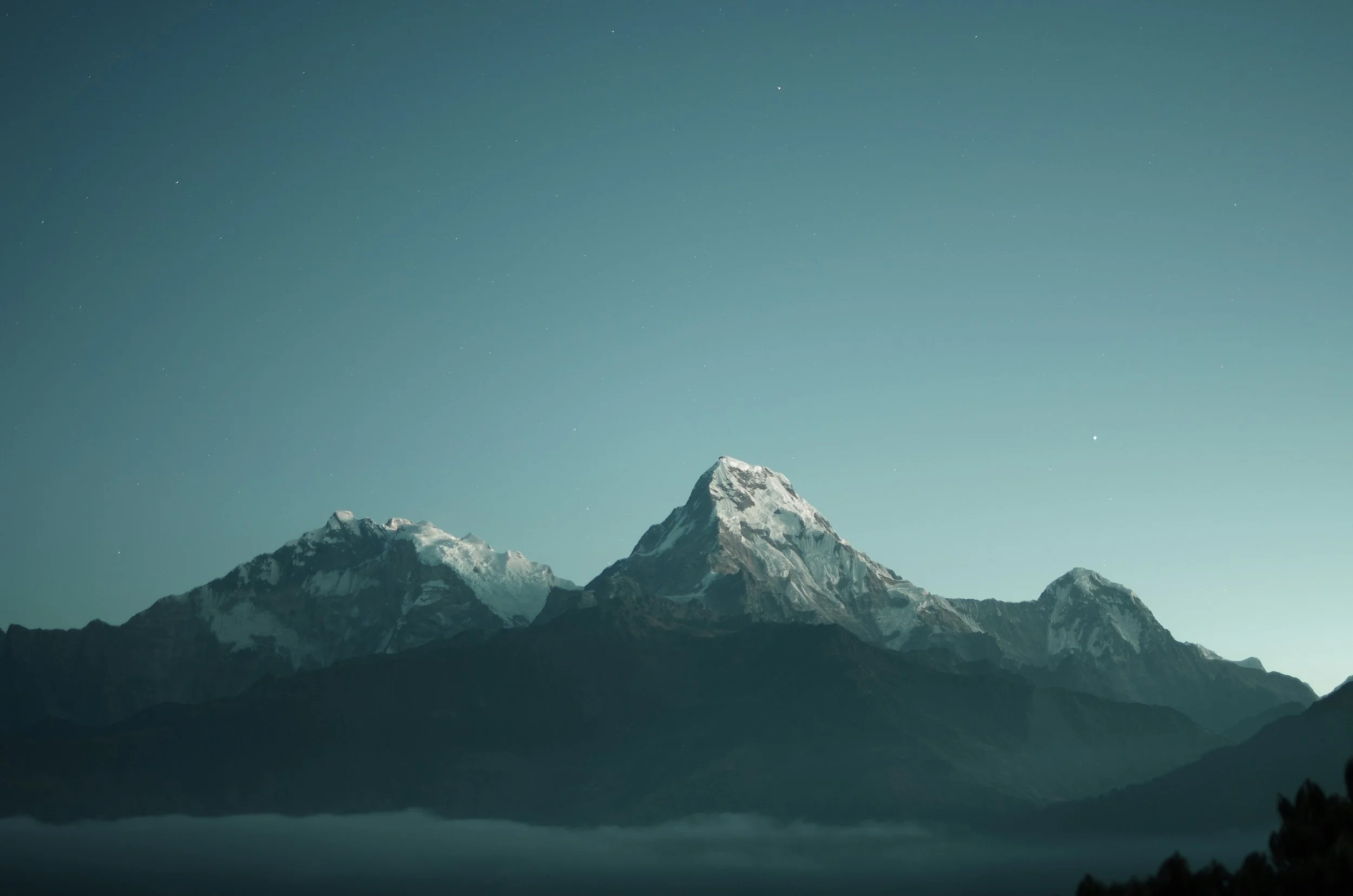 Snow-capped mountains at night with a starry sky.