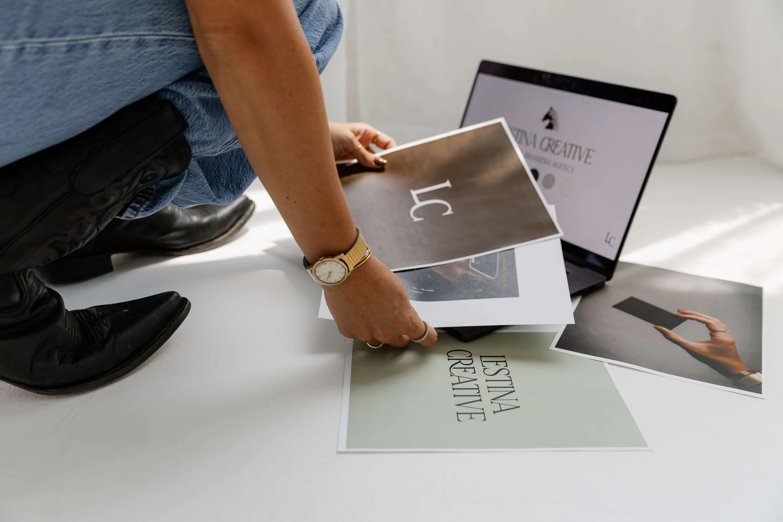 A young woman wearing a luxury watch shuffles through images of her new branding and logo.