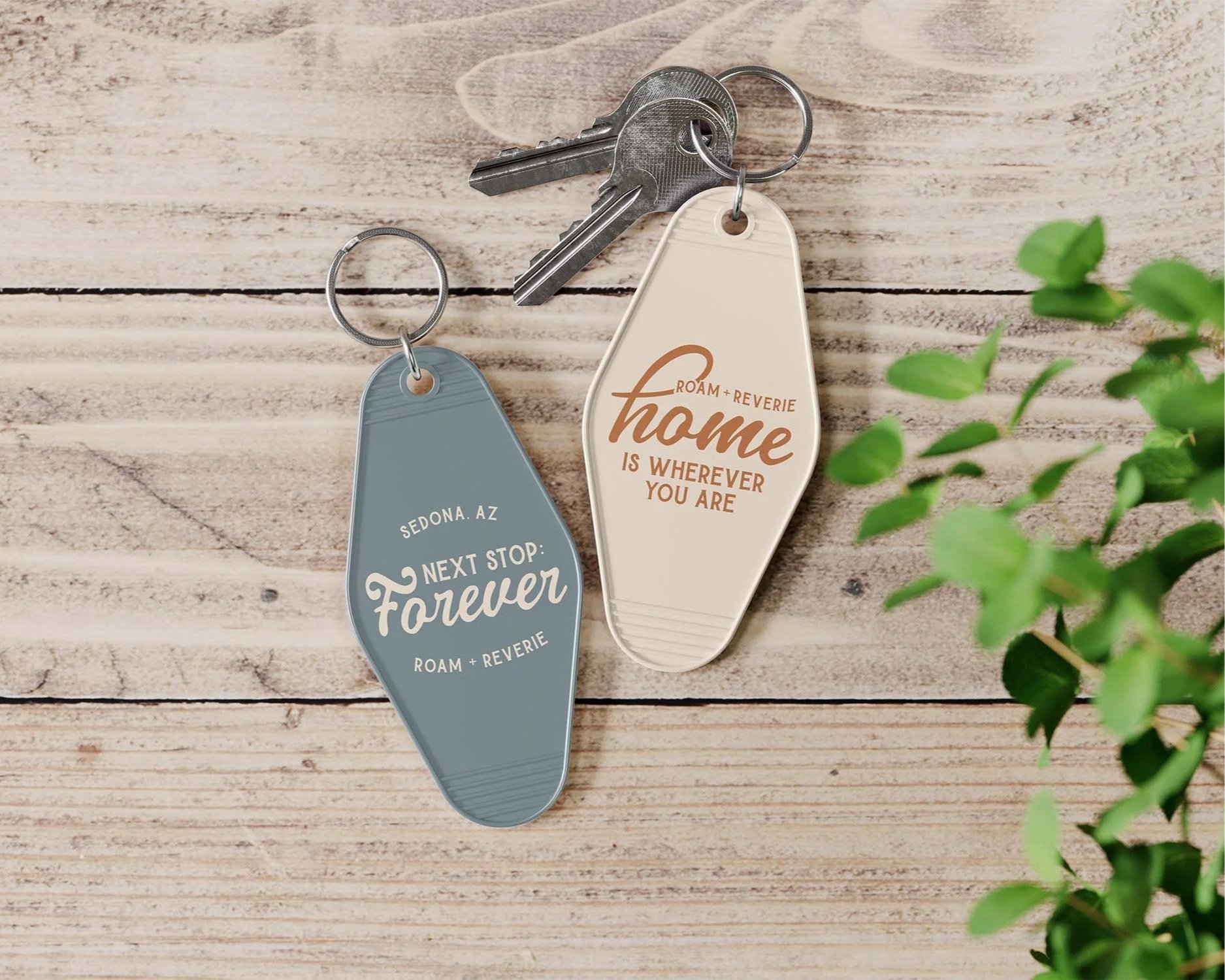 Custom keychains for an elopement photographer brand displayed on a white wood background.
