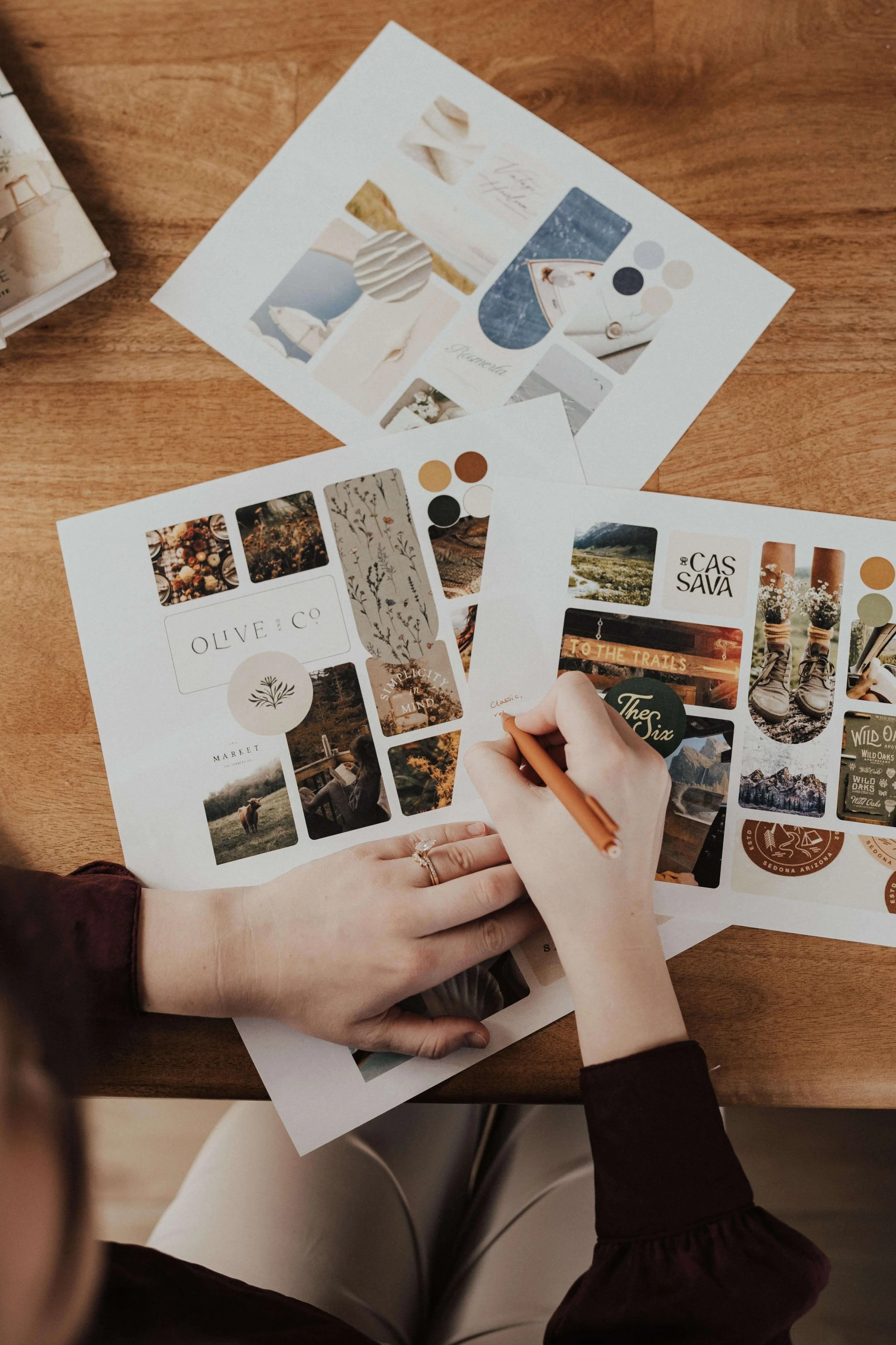 Hands writing on printed visual mood boards for a brand identity project.