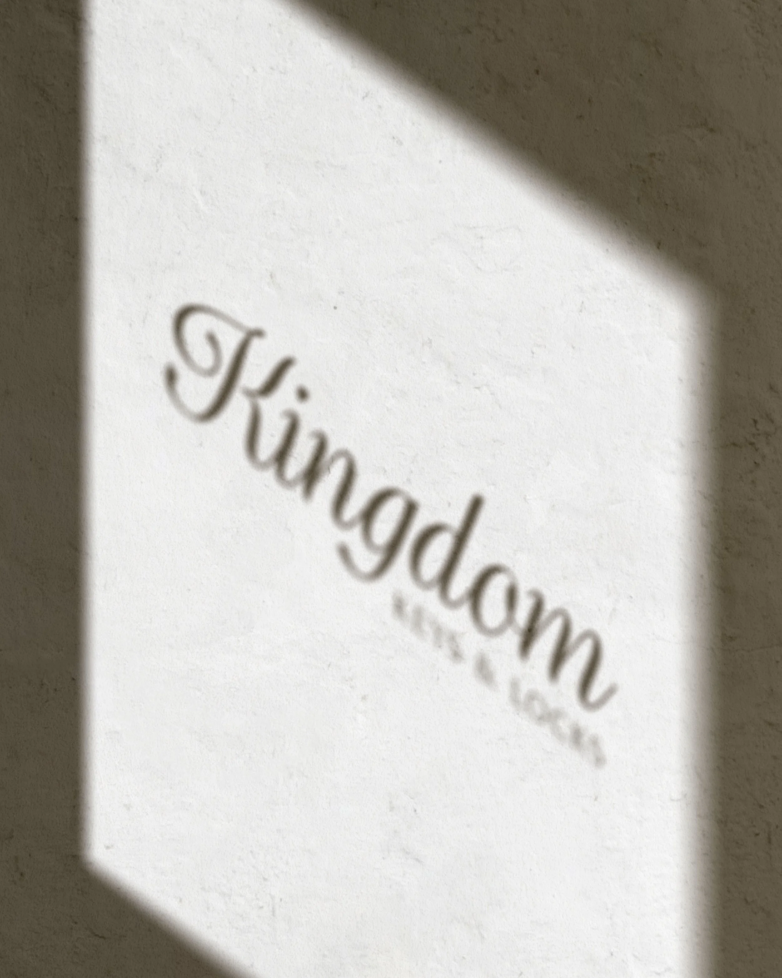 A shadow of the Kingdom Keys & Locks logo is cast on a blank white wall.