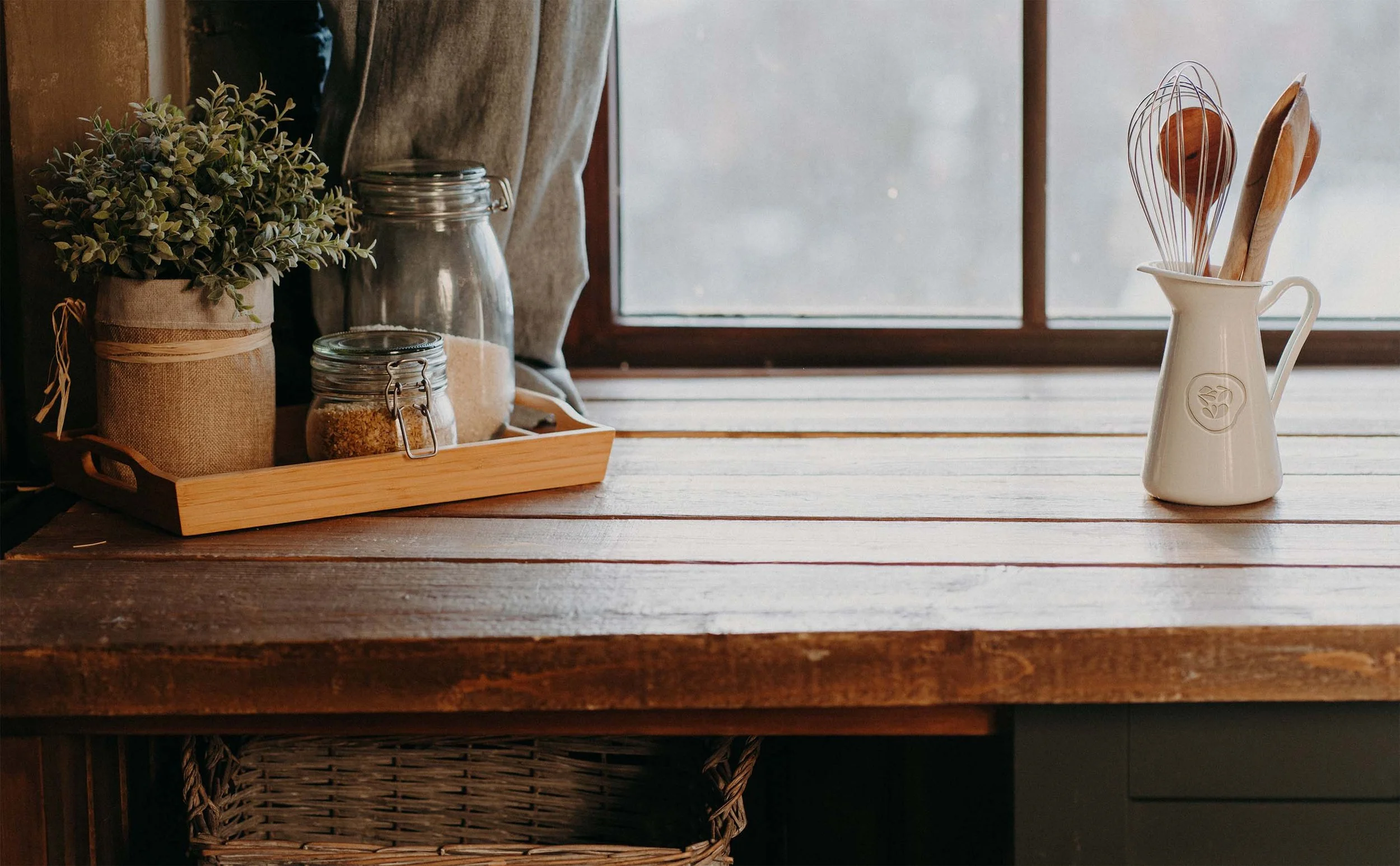 A scene in a farmhouse style kitchen with a utensil holder featuring the Whole Table logo mark.
