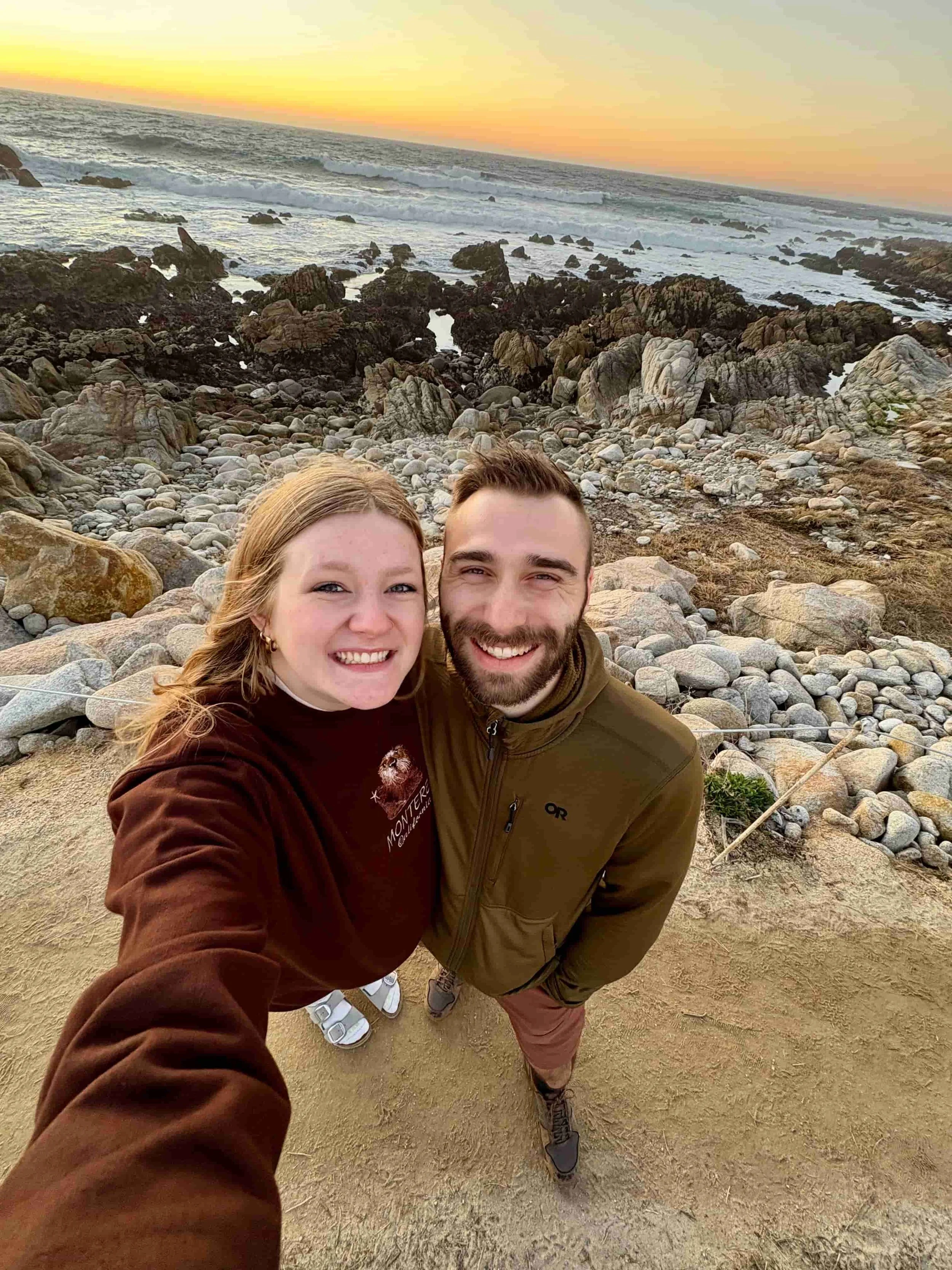 A young entrepreneur couple taking a selfie on a rocky beach.