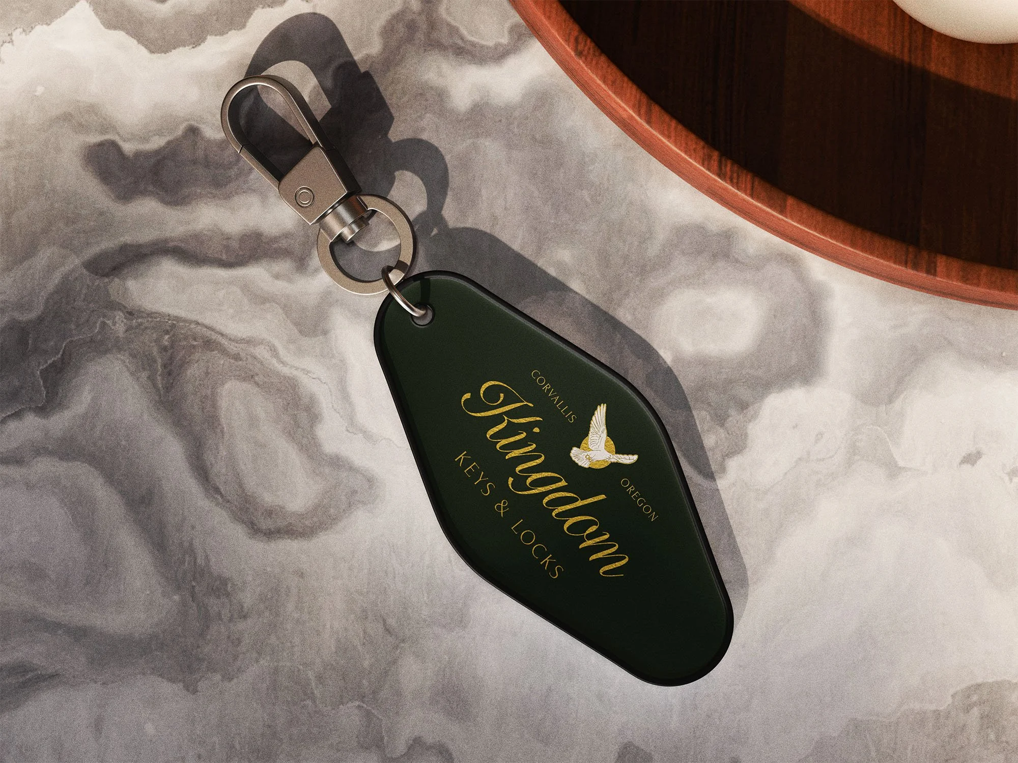 A green keychain with the Kingdom Keys and Locks logo lays on a white marble surface.