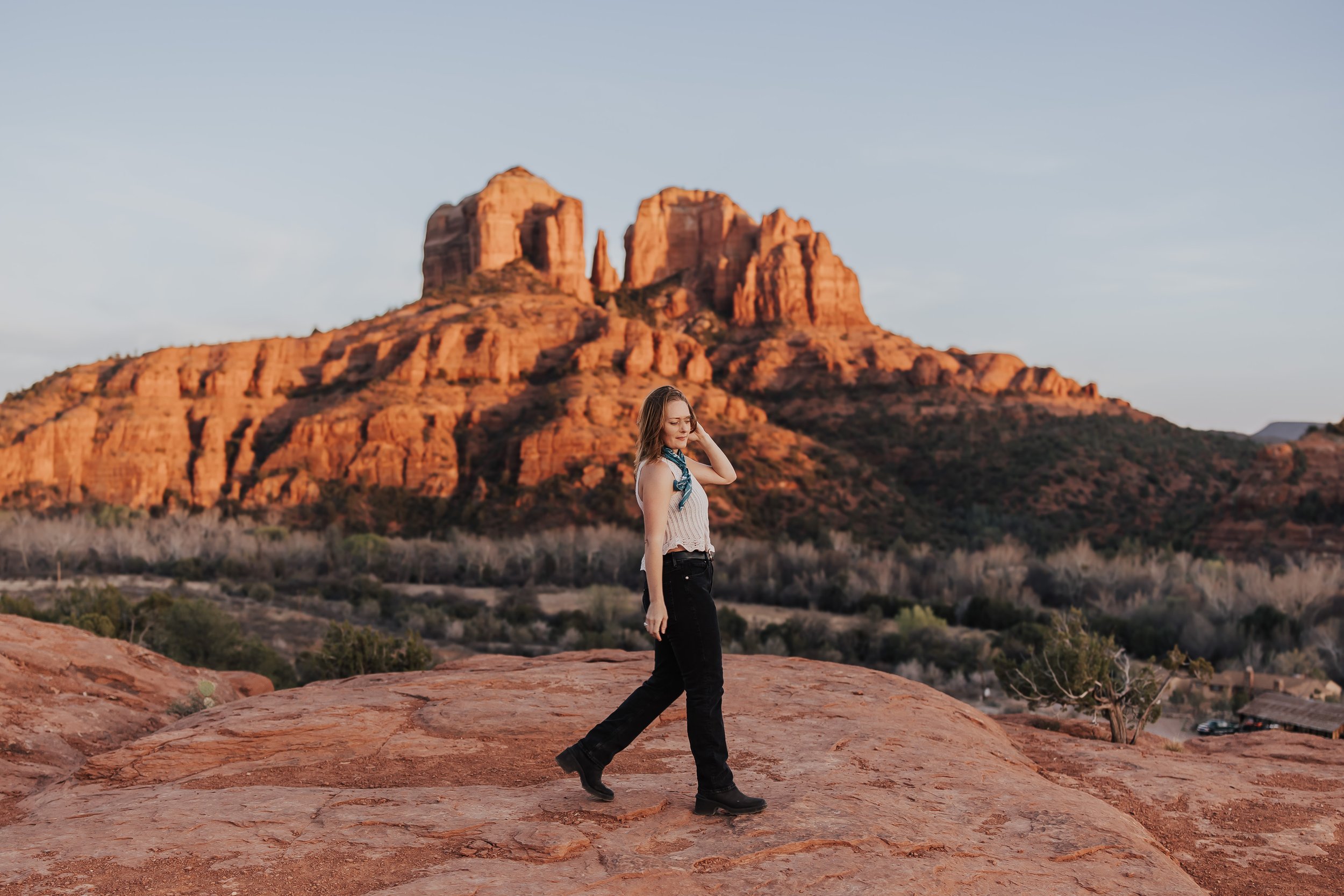 A wedding elopement photographer walks in front of a rock formation in Sedona, Arizona.