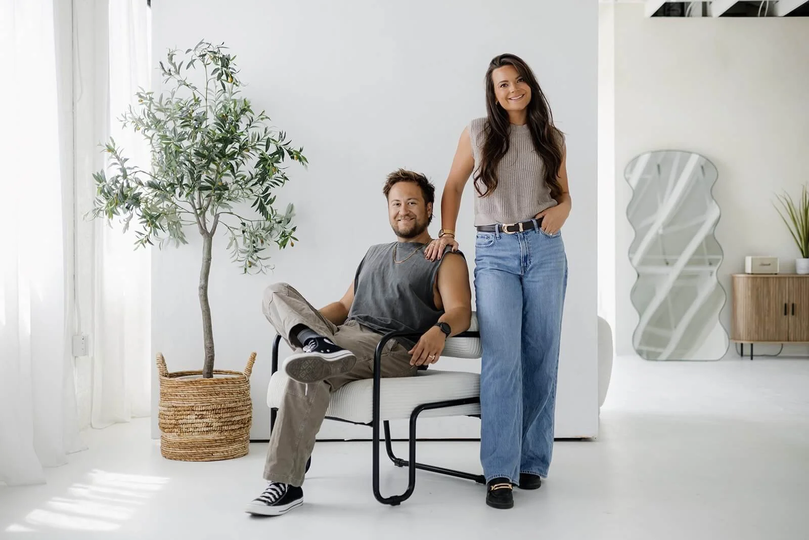 Two professional videographer and photographers pose together in a brightly lit studio setting.