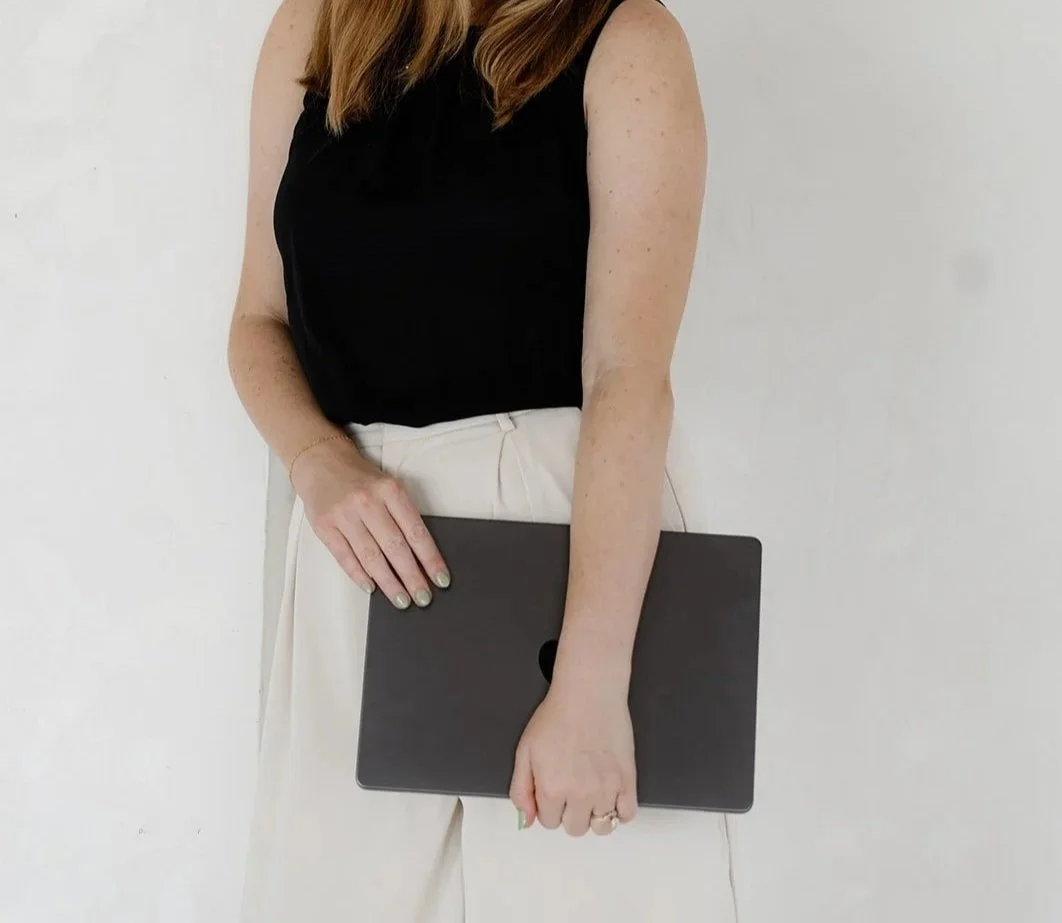 Aliya holding a laptop where she does brand design for small businesses.