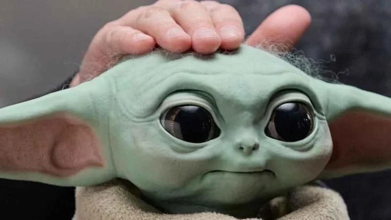 Head of the Ultimate Grogu toy from Hasbro Entertainment. Ultimate Grogu is life-size and has multiple functions as an animatronic. A hand is resting in his head for the promotional images.  Image Source: Hasbro