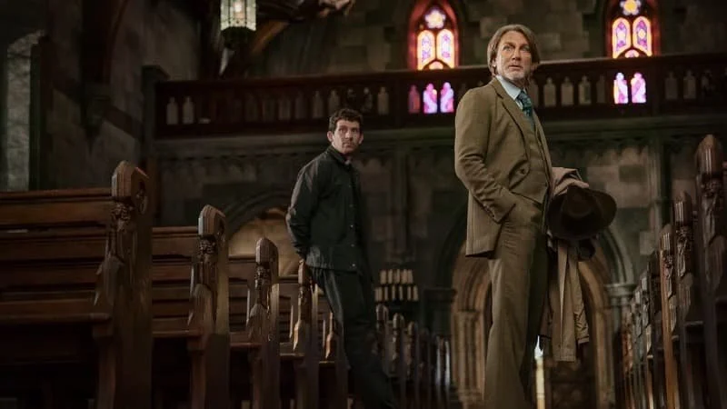 Josh O’Connor as Father Jude and Daniel Craig as Benoit Blanc