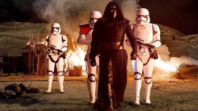 Kylo Ren (played by Adam Driver) walking on Jakku with a battalion of Stormtroopers.