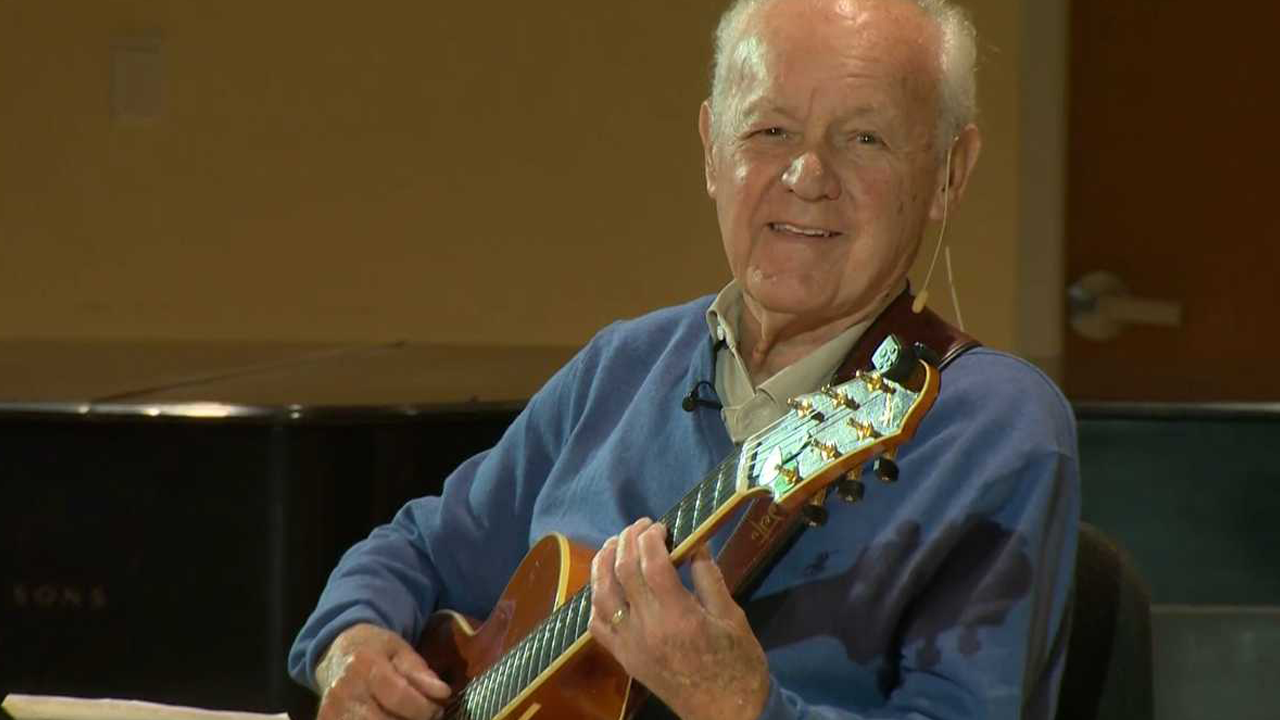 Joe Negri playing the guitar in a classroom studio setting