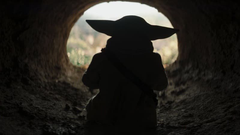 Grogu crawling through a small hole