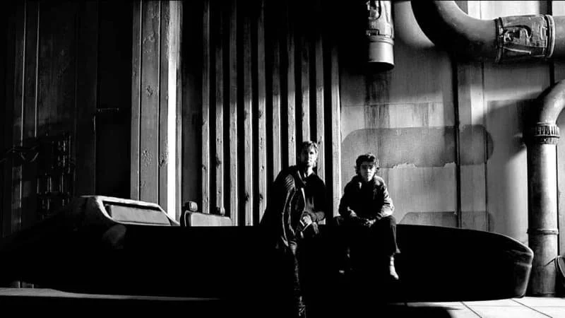 Promotional image for Star Wars: Starfighter featuring Ryan Gosling and Flynn Gray sitting on some type of planetary travel ship, the background industrial-looking. The image is in black and white.  Image Source: IMDb