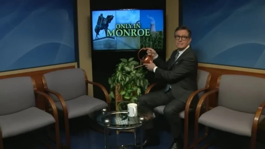 Stephen Colbert on the show Only in Monroe in May 2026, watering a plant and looking to the camera with a smile.