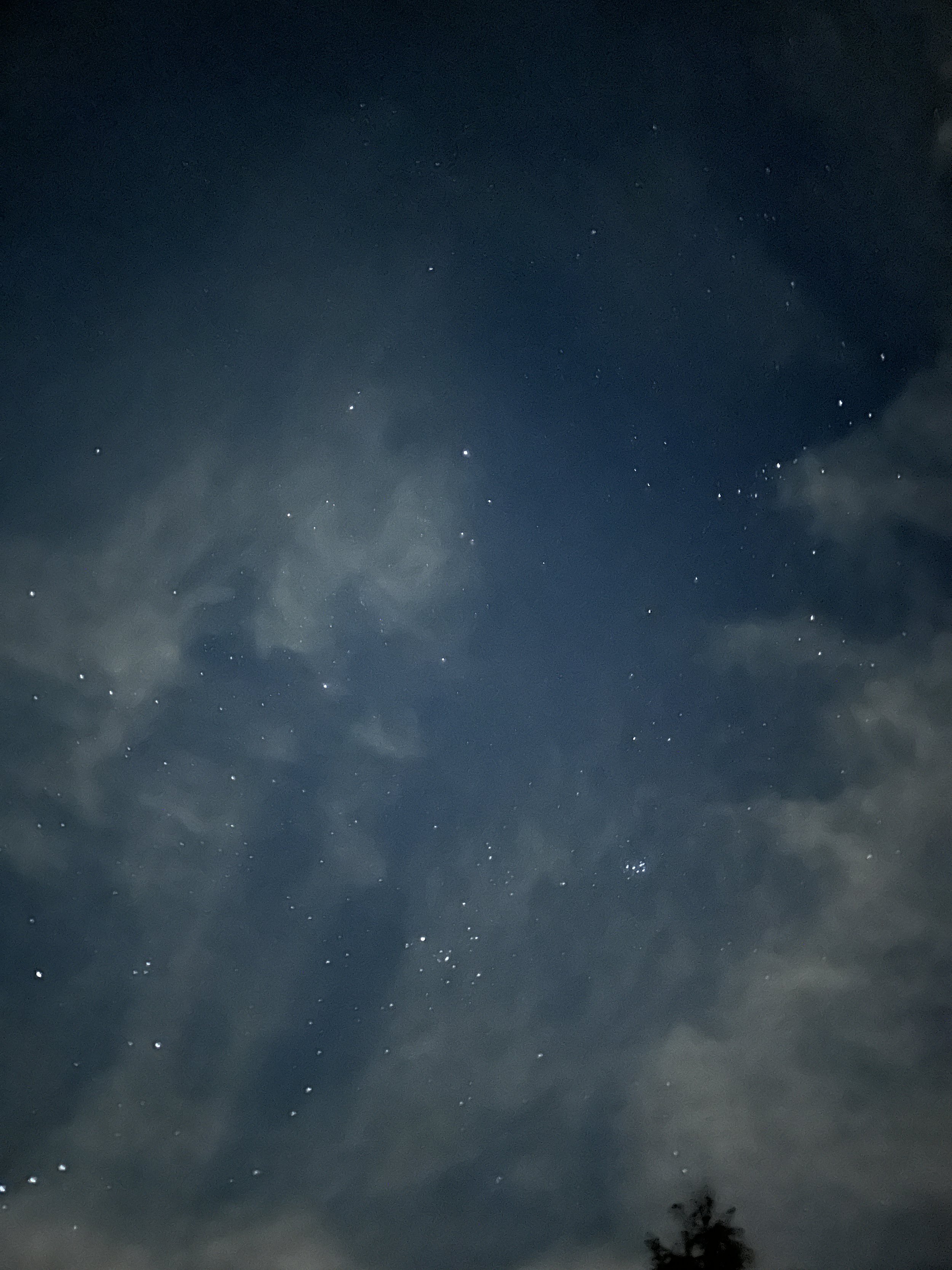 A midnight blue sky is dotted by tiny white starts and translucent whisps of white clouds.