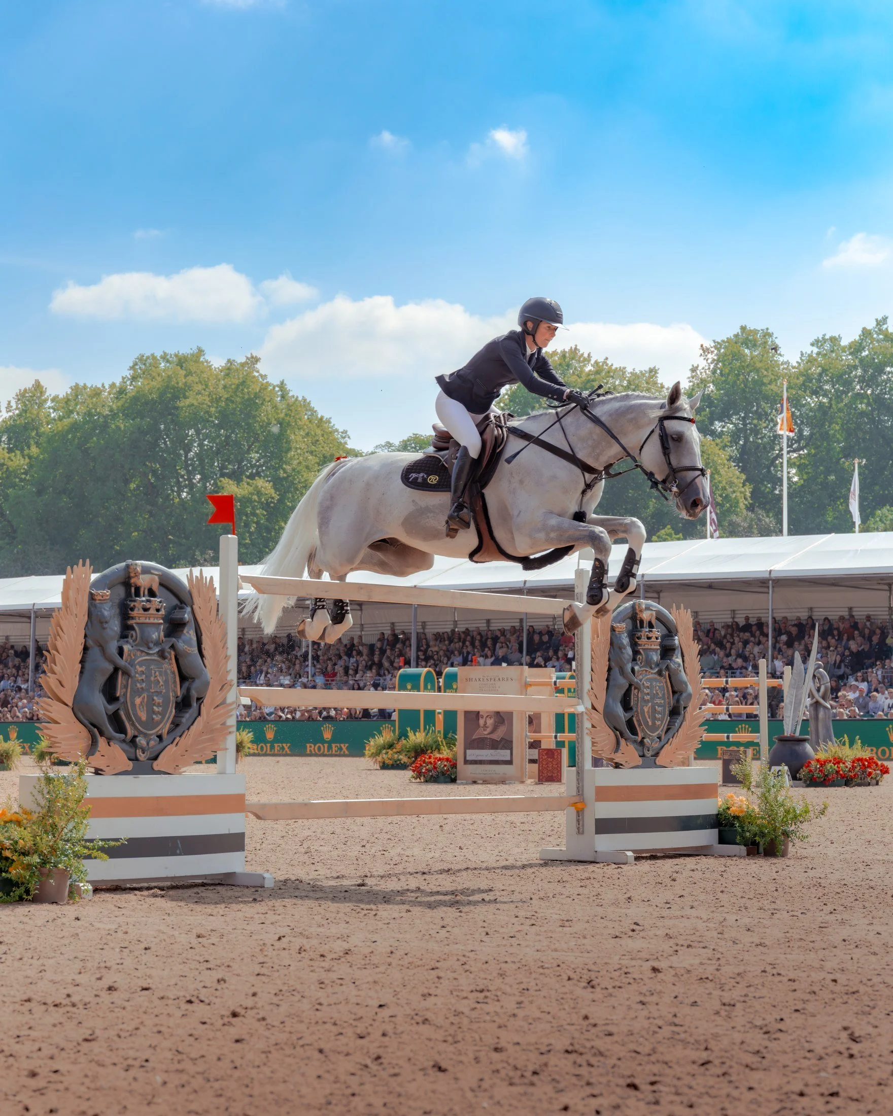 A rider clears a jump on a grey horse at the Royal Windsor Horse Show.