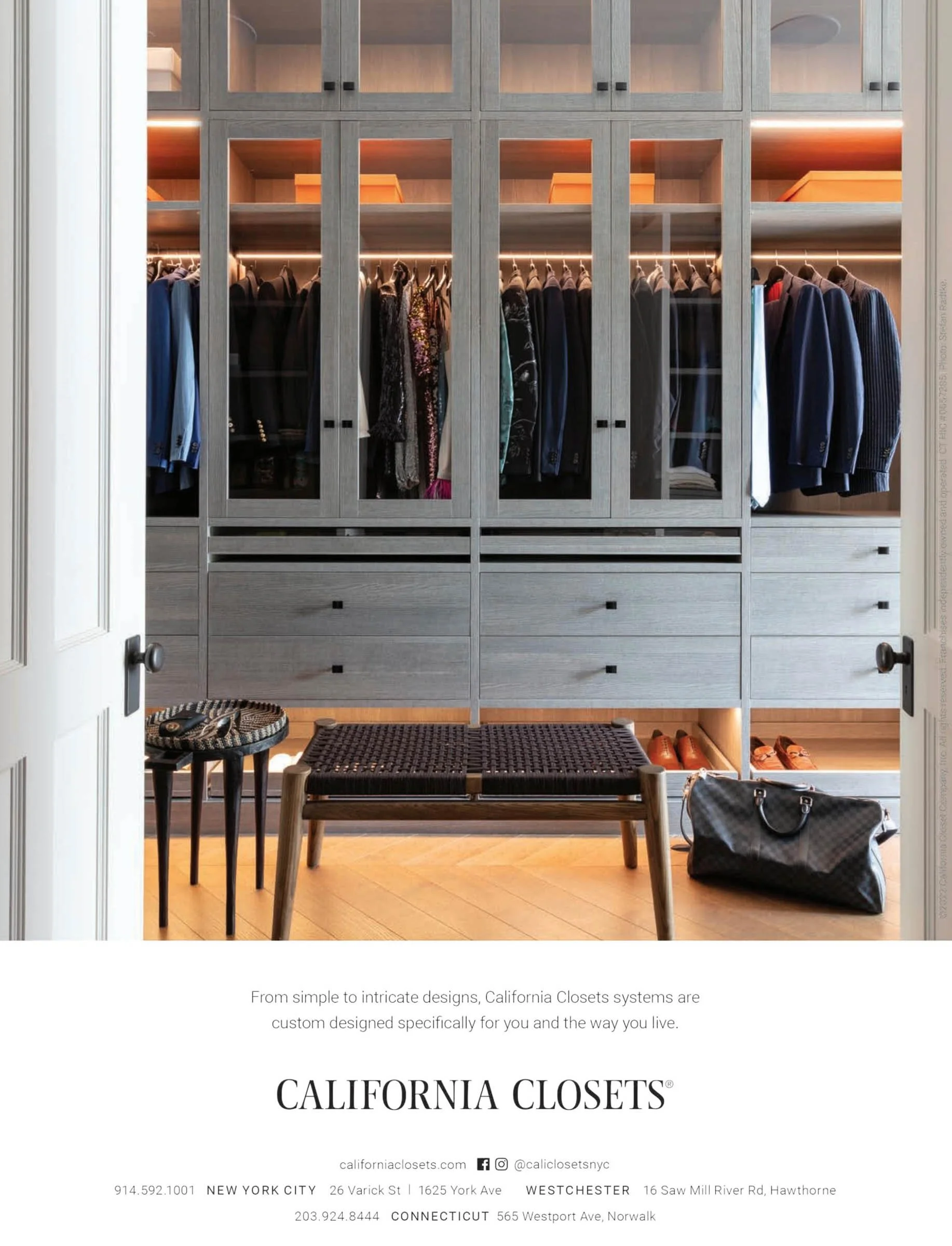 Modern closet with gray wood cabinetry, displaying organized clothing and accessories, with an upholstered bench in front and a bag on the floor. Advert for California Closets.