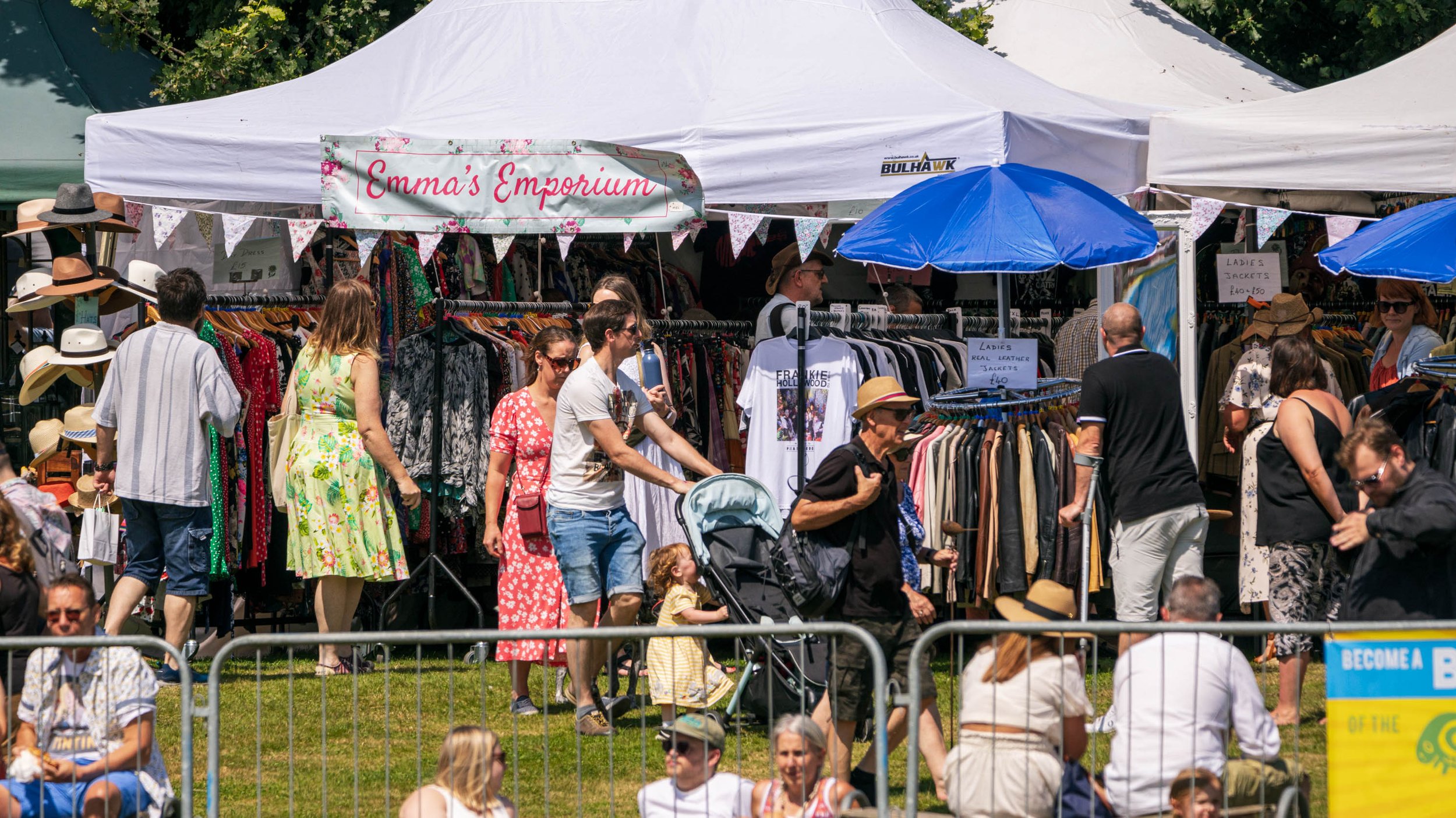 Public looking around clothing stalls under gazebos.