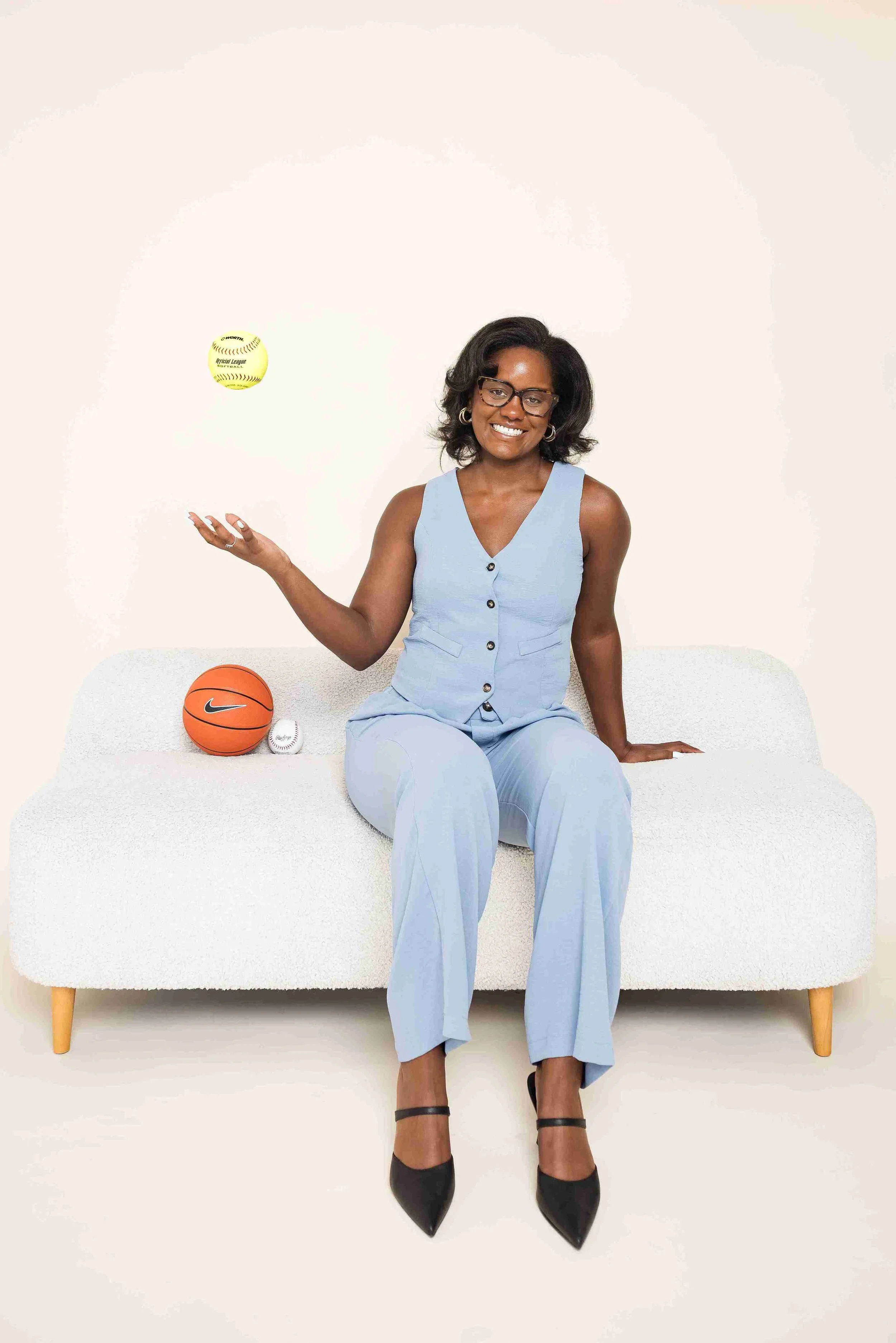 Peyton Stokes-Sutton's headshot. She is sitting on a couch with sports balls next to her.