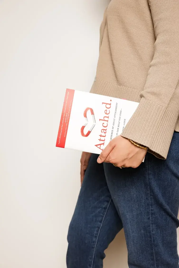 Hajrah Javed holding the Attached. book in her hand representing couples therapy and dating issues in Richardson Texas