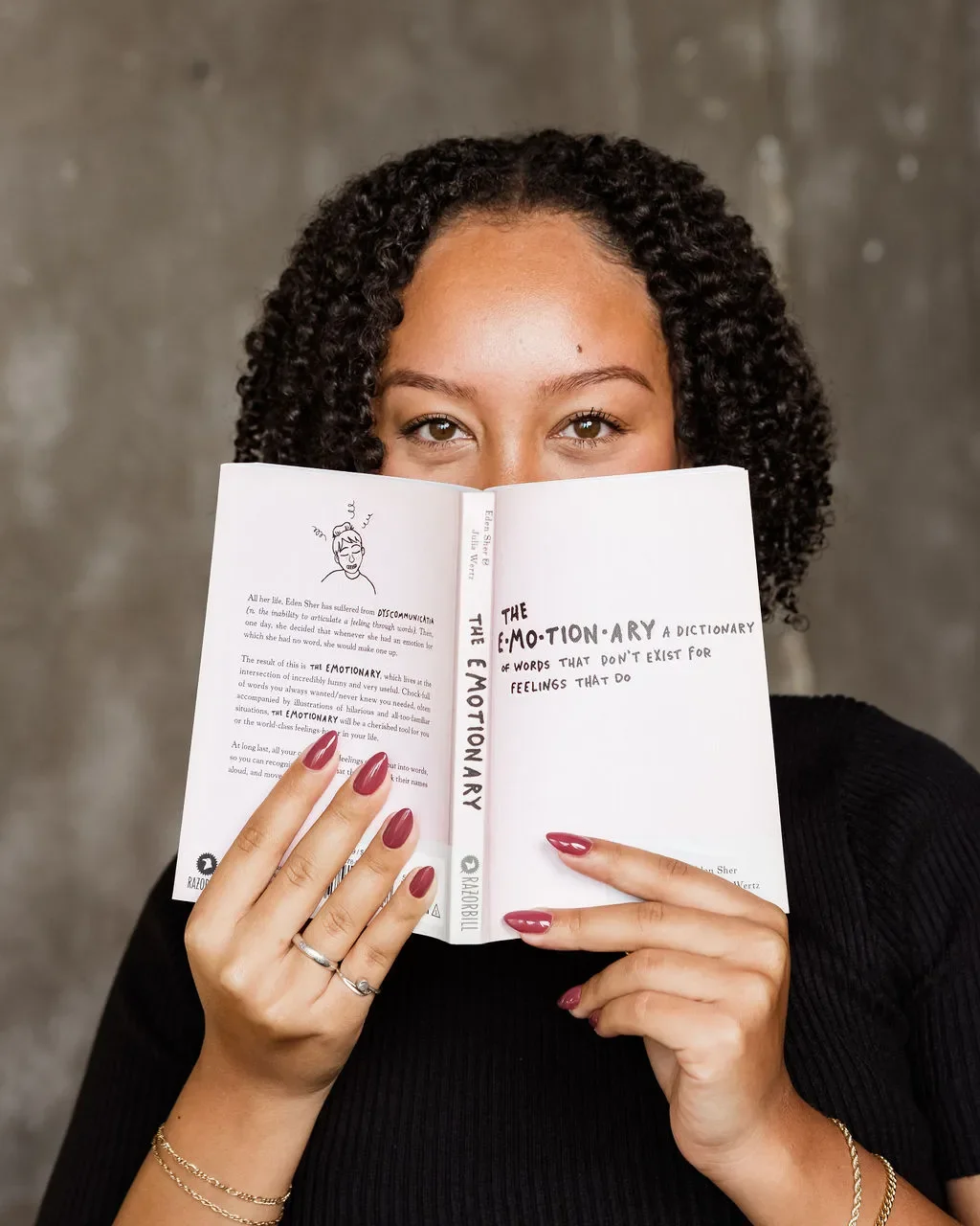 A mixed therapist - Black and Asian - holding the book The Emotionary to represent anxiety and depression in Katy Texas