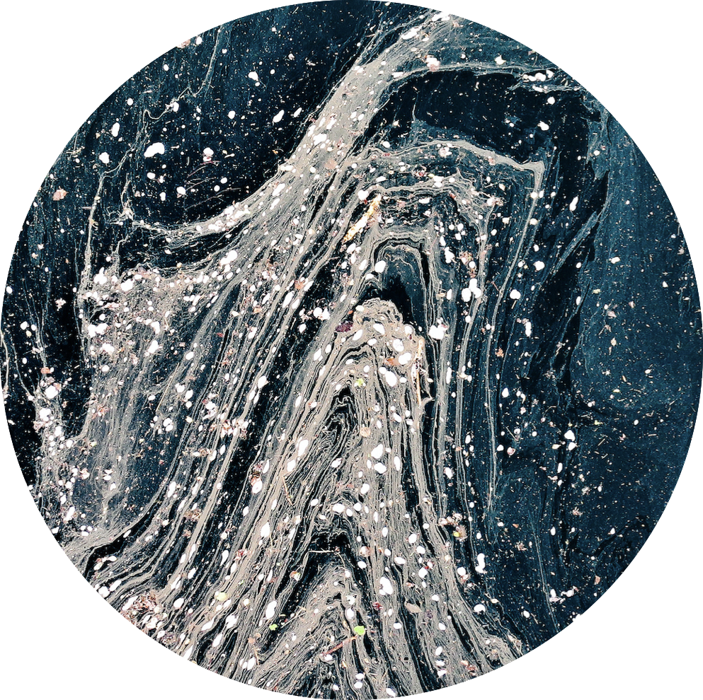 Close-up of a dark, textured surface with white specks and streaks, appearing as a marble or stone pattern.