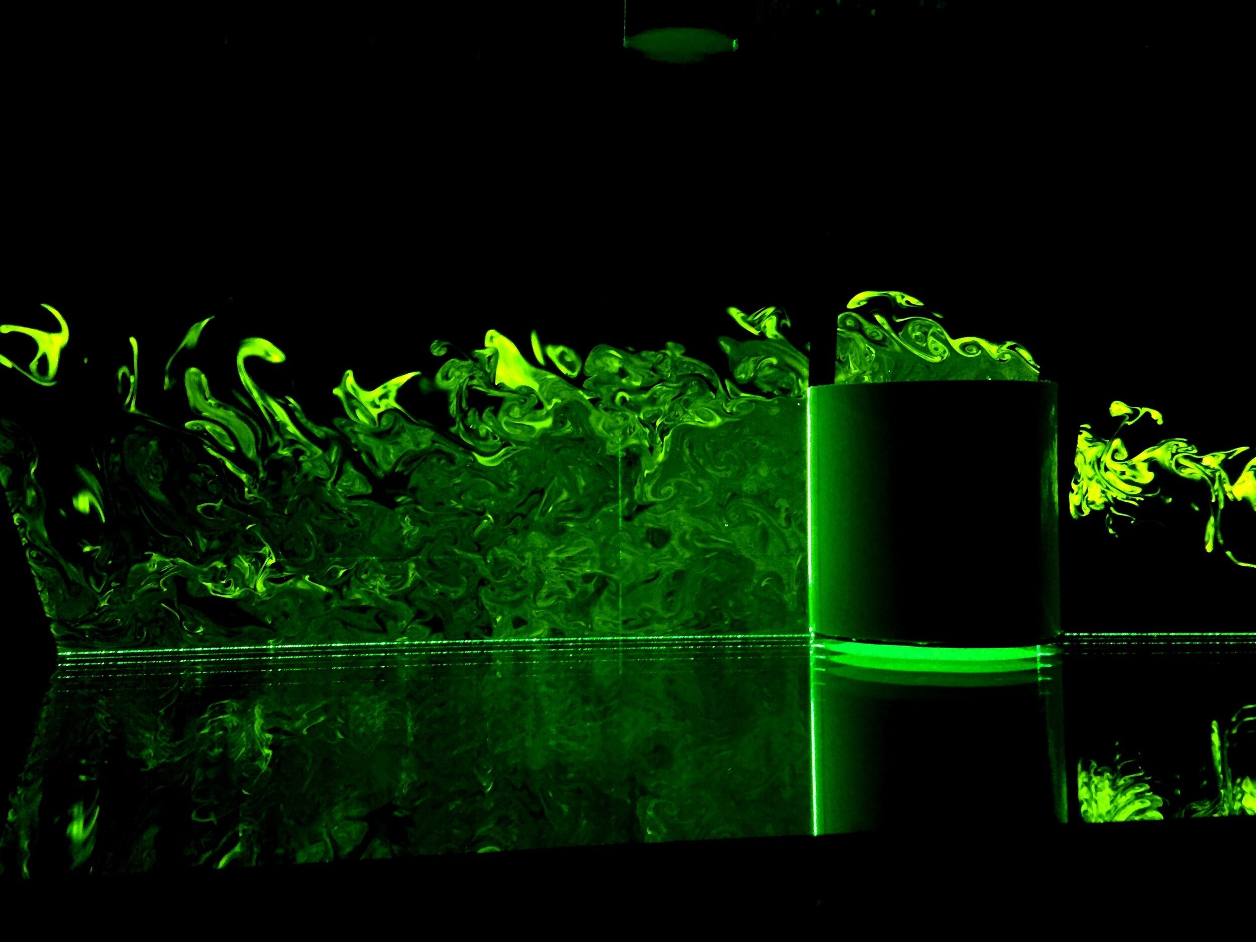 turbulent odor plumes visualized using laser-based diagnostics. the odor plume fluoresces green against a black backdrop.