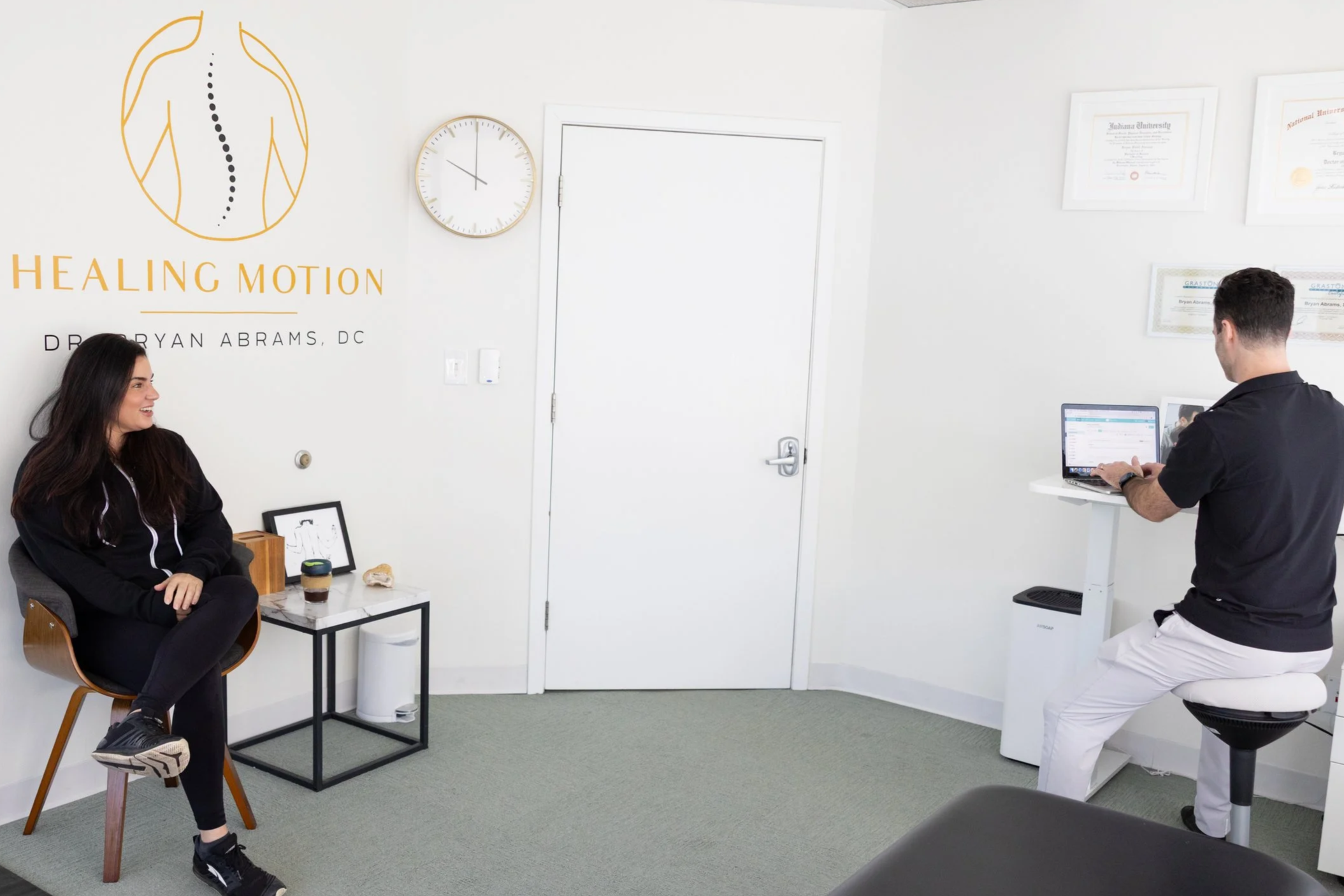 Dr. Bryan Abrams discussing care with a patient during a chiropractic consultation at Healing Motion in Bloomfield Hills, Michigan.