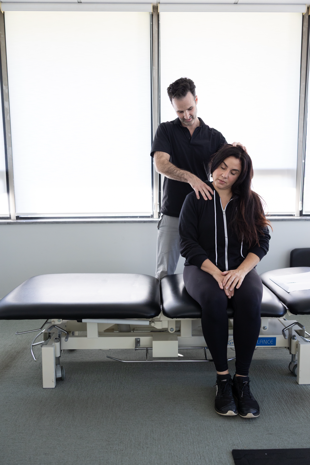 Dr. Bryan Abrams performing myofascial release on a patient's neck and shoulder at Healing Motion in Bloomfield Hills, Michigan