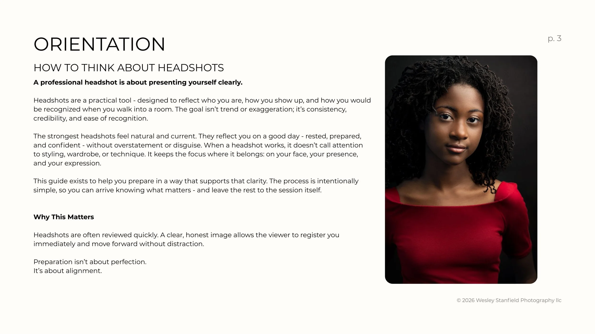 A young woman with natural curly hair wearing a red top, posing against a dark background.