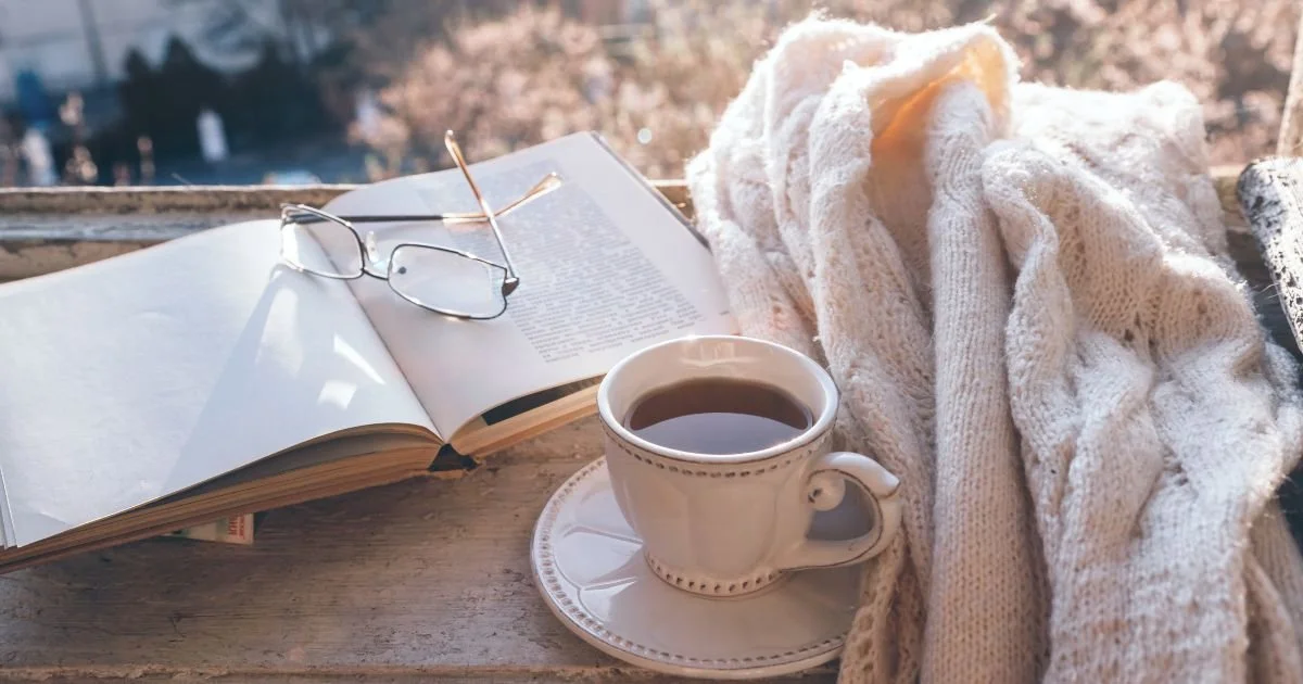 an open Bible, a cup of hot tea, and a fuzzy blanket resting on a tabletop